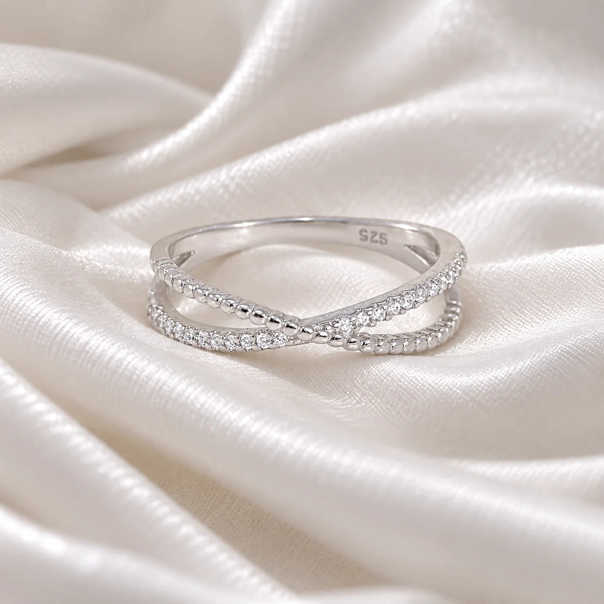 Infinity_ring_in_sterling_silver_with_criss_cross_design_and_lab_grown_diamonds_at_front_angle_view_on_soft_fabric_background