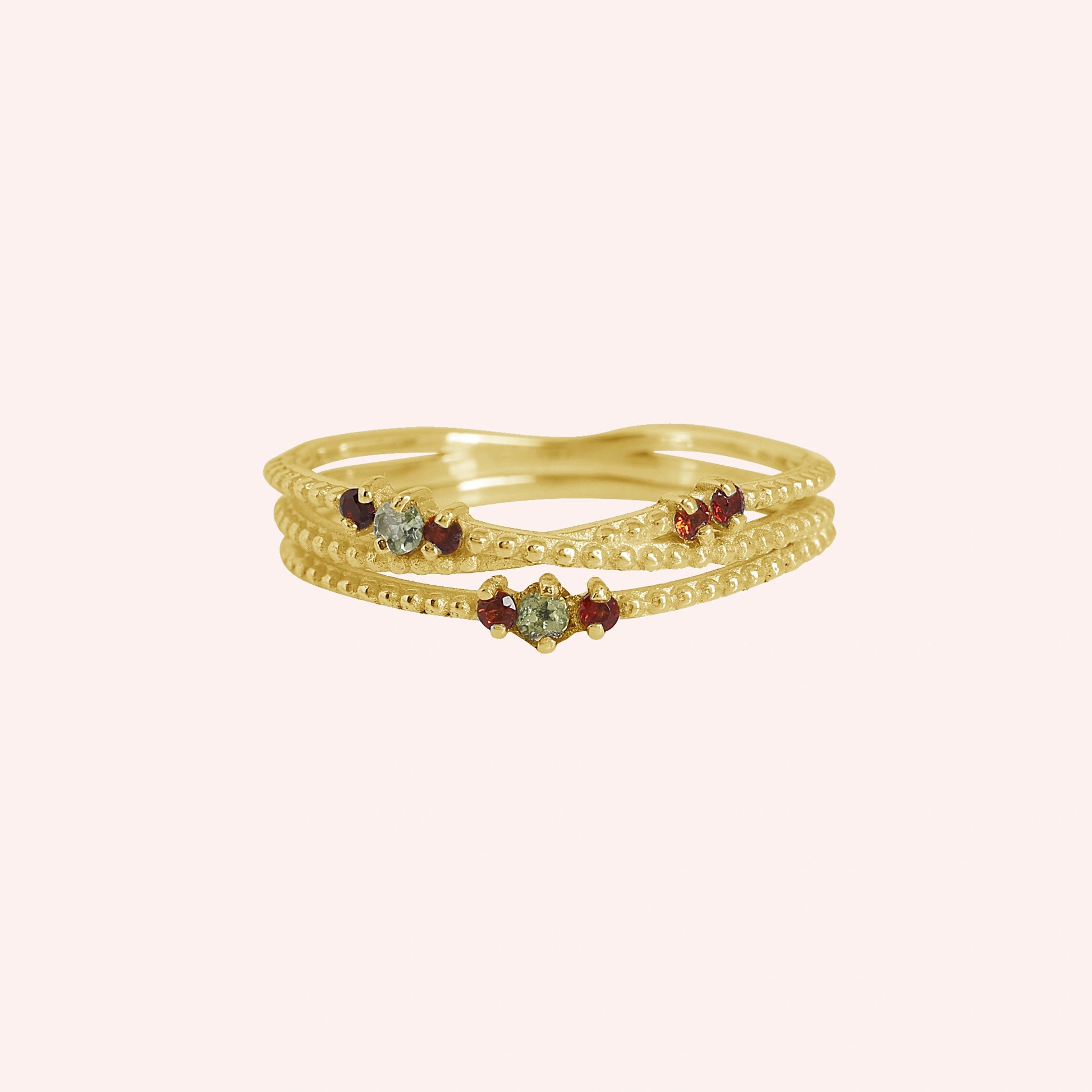 Infinity_ring_gold_plated_silver_band_with_red_and_green_stones_front_angle_view_on_solid_pink_background