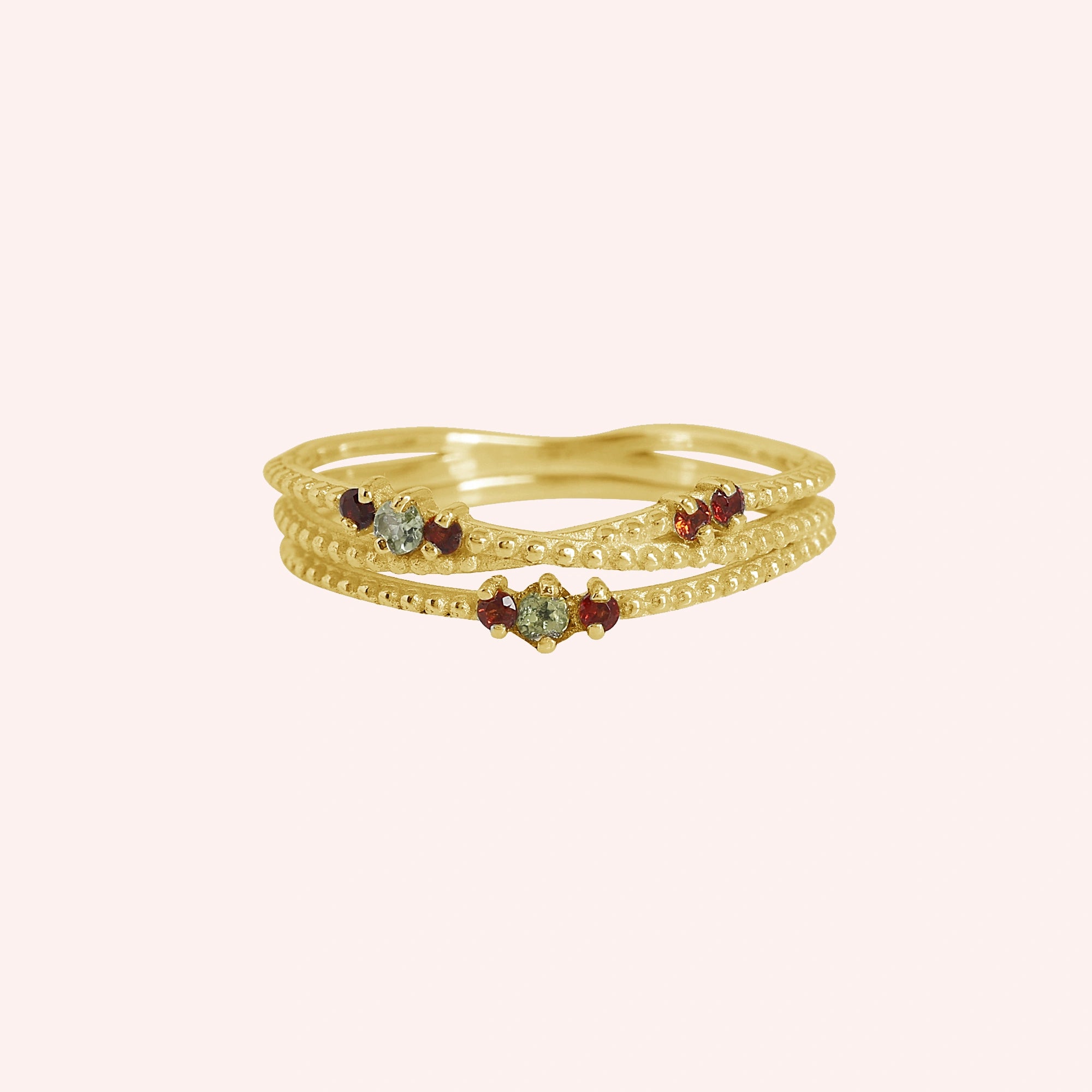 Infinity_ring_gold_plated_silver_band_with_red_and_green_stones_front_angle_view_on_solid_pink_background