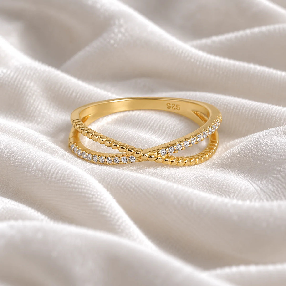 Infinity_ring_in_gold_plated_silver_with_criss_cross_design_and_lab_grown_diamonds_at_front_angle_view_on_soft_fabric_background