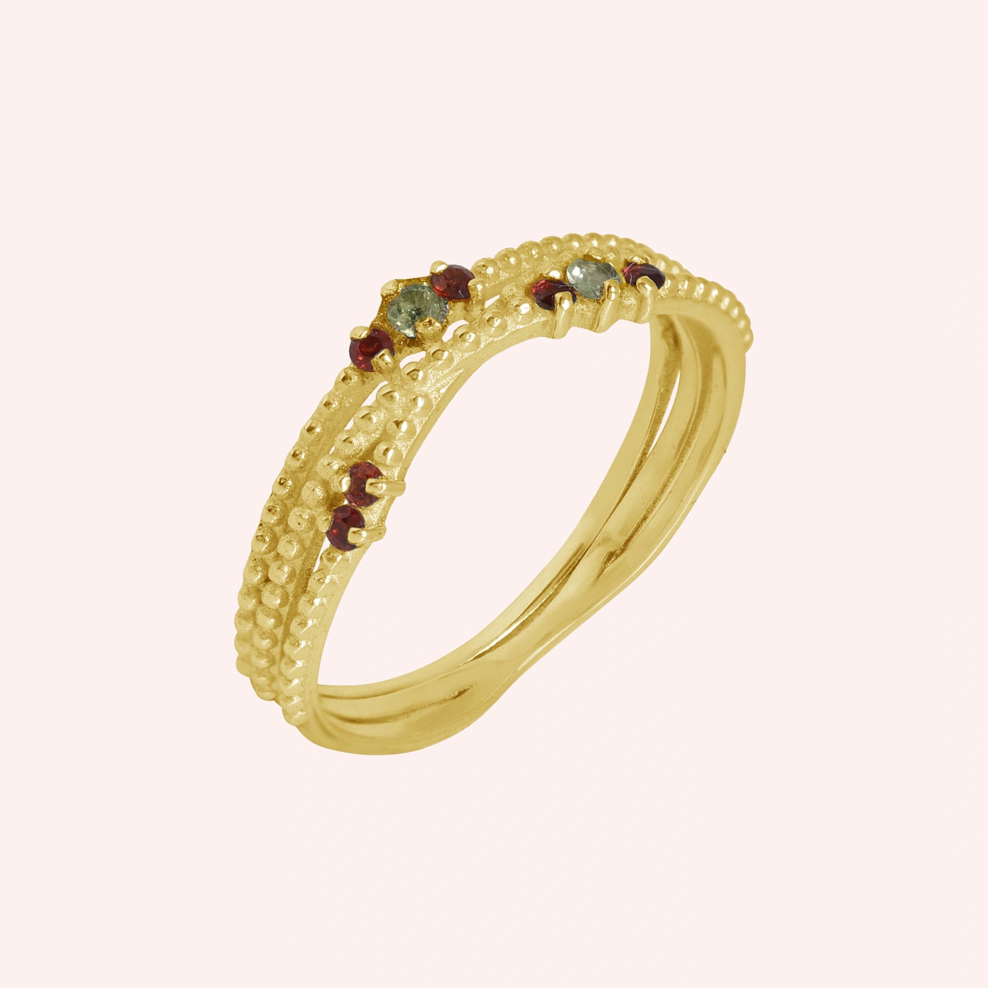 Infinity_ring_gold_plated_silver_band_with_red_and_green_stones_slightly_angled_view_on_soft_pink_background