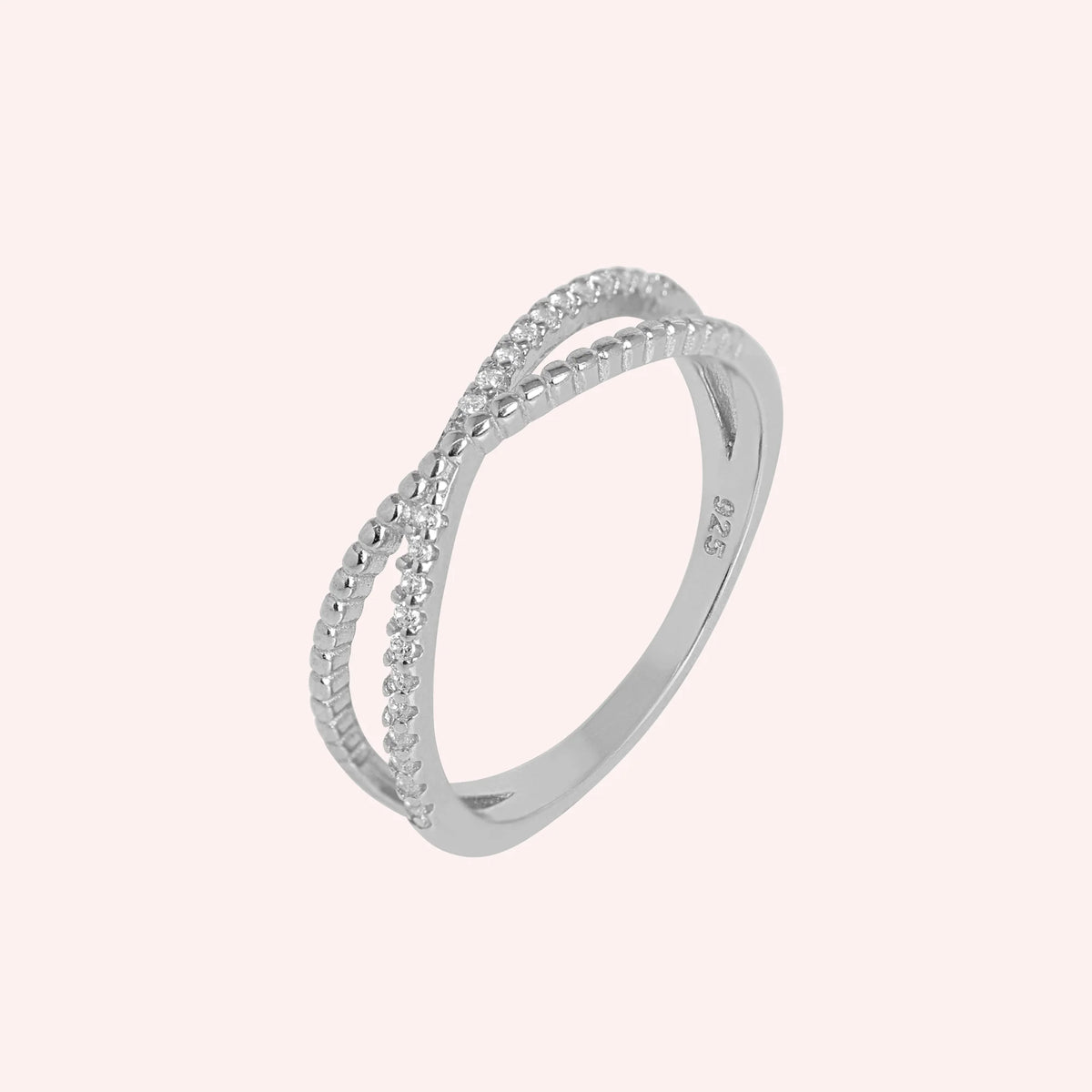 Infinity_ring_in_sterling_silver_with_criss_cross_design_and_lab_grown_diamonds_at_side_angle_view_on_solid_pink_background