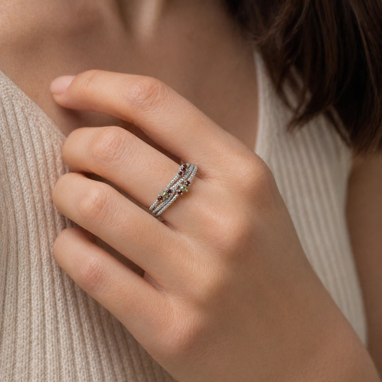 Infinity_ring_sterling_silver_band_with_red_and_green_stones_worn_by_a_model