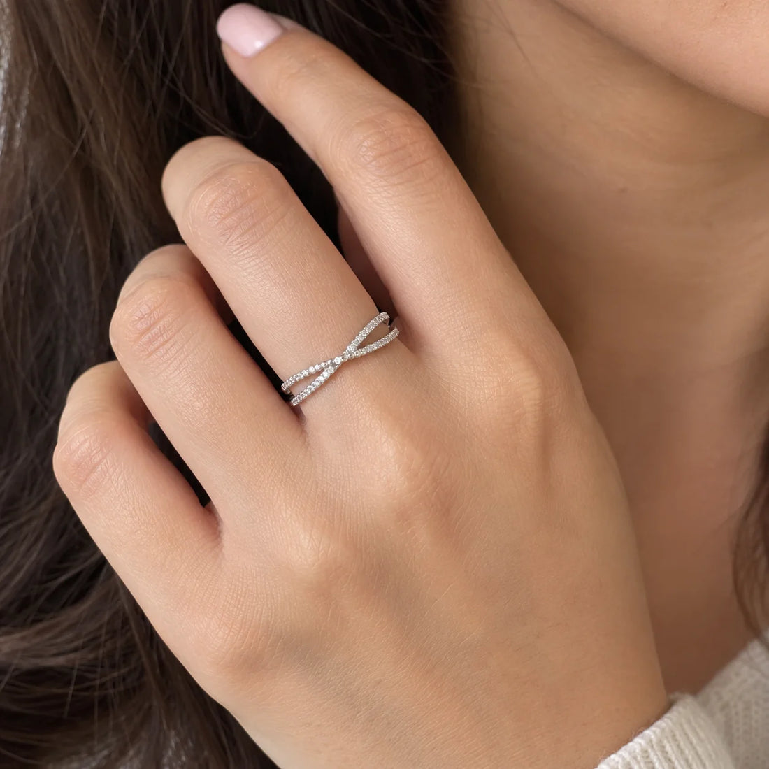 Infinity_ring_in_gold_plated_silver_with_criss_cross_design_and_CZ_stones_at_front_angle_view_on_soft_fabric_background