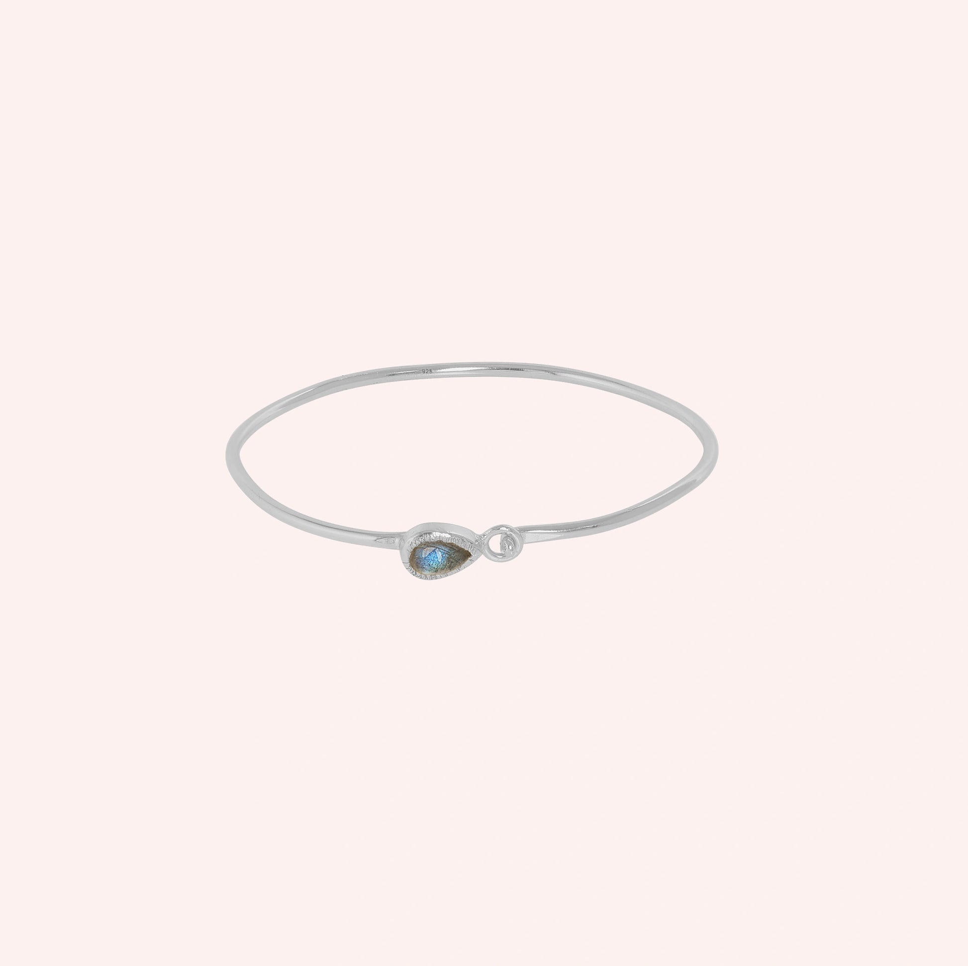 Labradorite_bracelet_in_sterling_silver_with_an_teardrop_labradorite_stone_at_front_angle_view_on_solid_pink_background