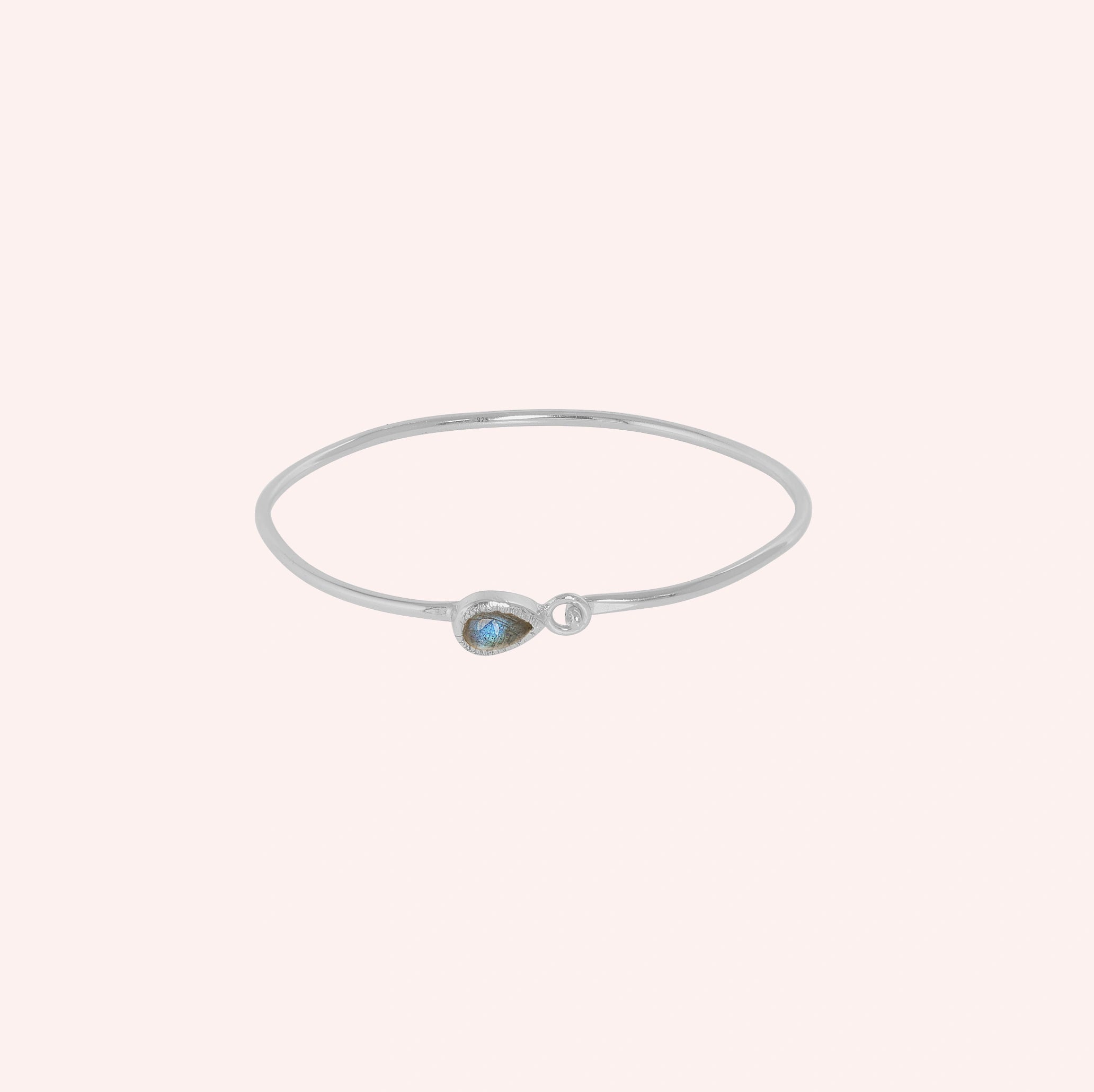Labradorite_bracelet_in_sterling_silver_with_an_teardrop_labradorite_stone_at_front_angle_view_on_solid_pink_background
