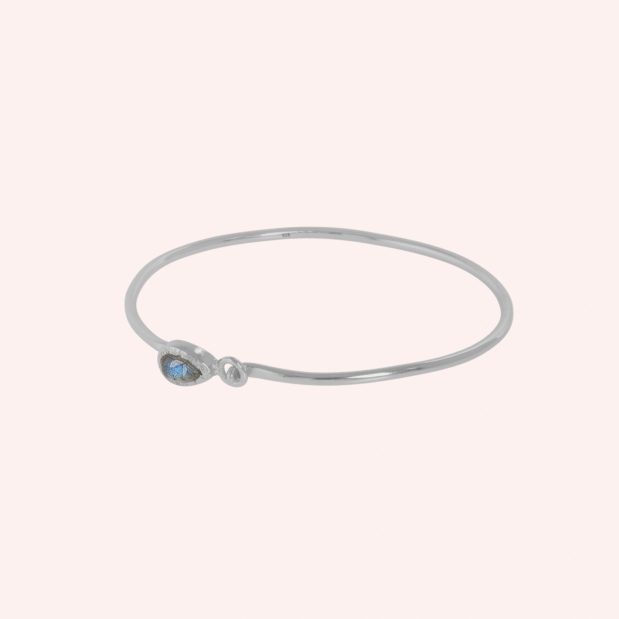 Labradorite_bracelet_in_sterling_silver_with_an_teardrop_labradorite_stone_at_slight_angle_view_on_solid_pink_background