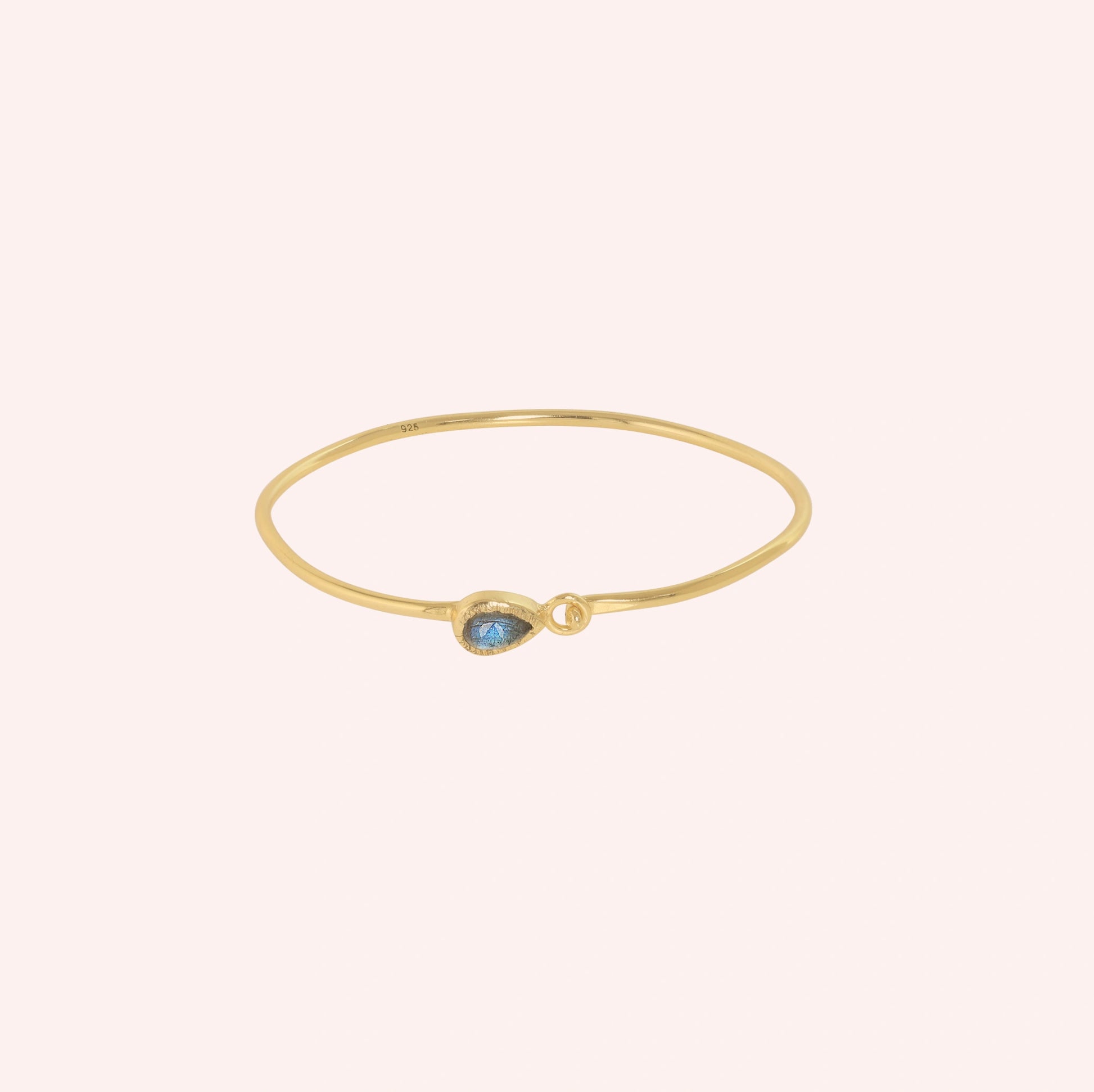 Labradorite_bracelet_in_gold_plated_silver_with_an_teardrop_labradorite_stone_at_front_angle_view_on_solid_pink_background