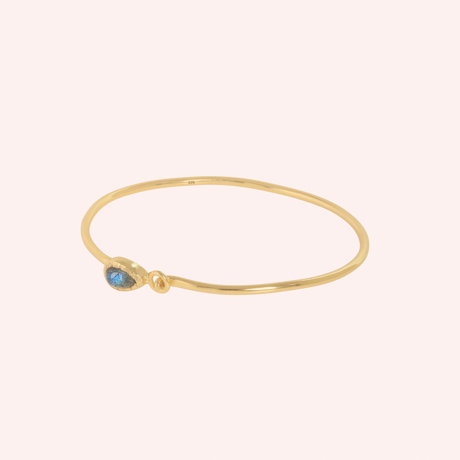 Labradorite_bracelet_in_gold_plated_silver_with_an_teardrop_labradorite_stone_at_slight_angle_view_on_solid_pink_background