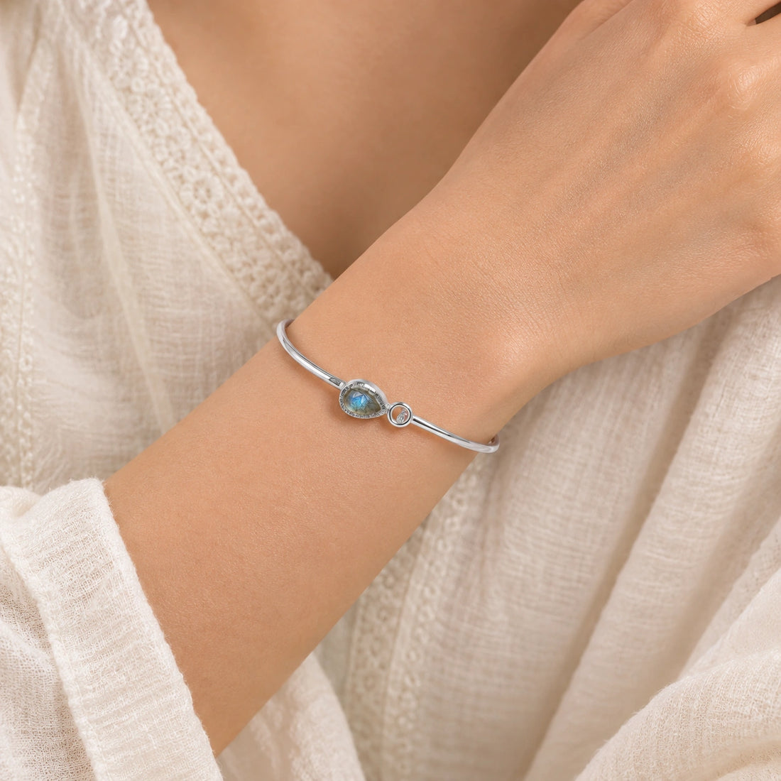Labradorite_bracelet_in_gold_plated_silver_with_an_teardrop_labradorite_stone_at_front_angle_view_on_soft_fabric_background