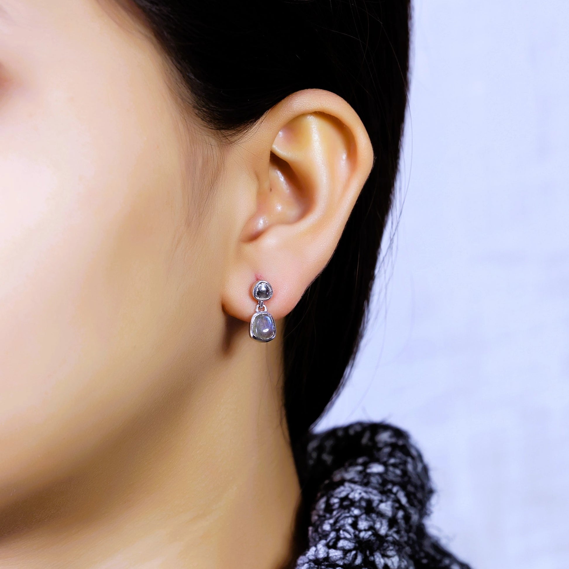Tiny earrings silver stud earrings with vibrant labradorite stones worn by model close up viewed from a side angle