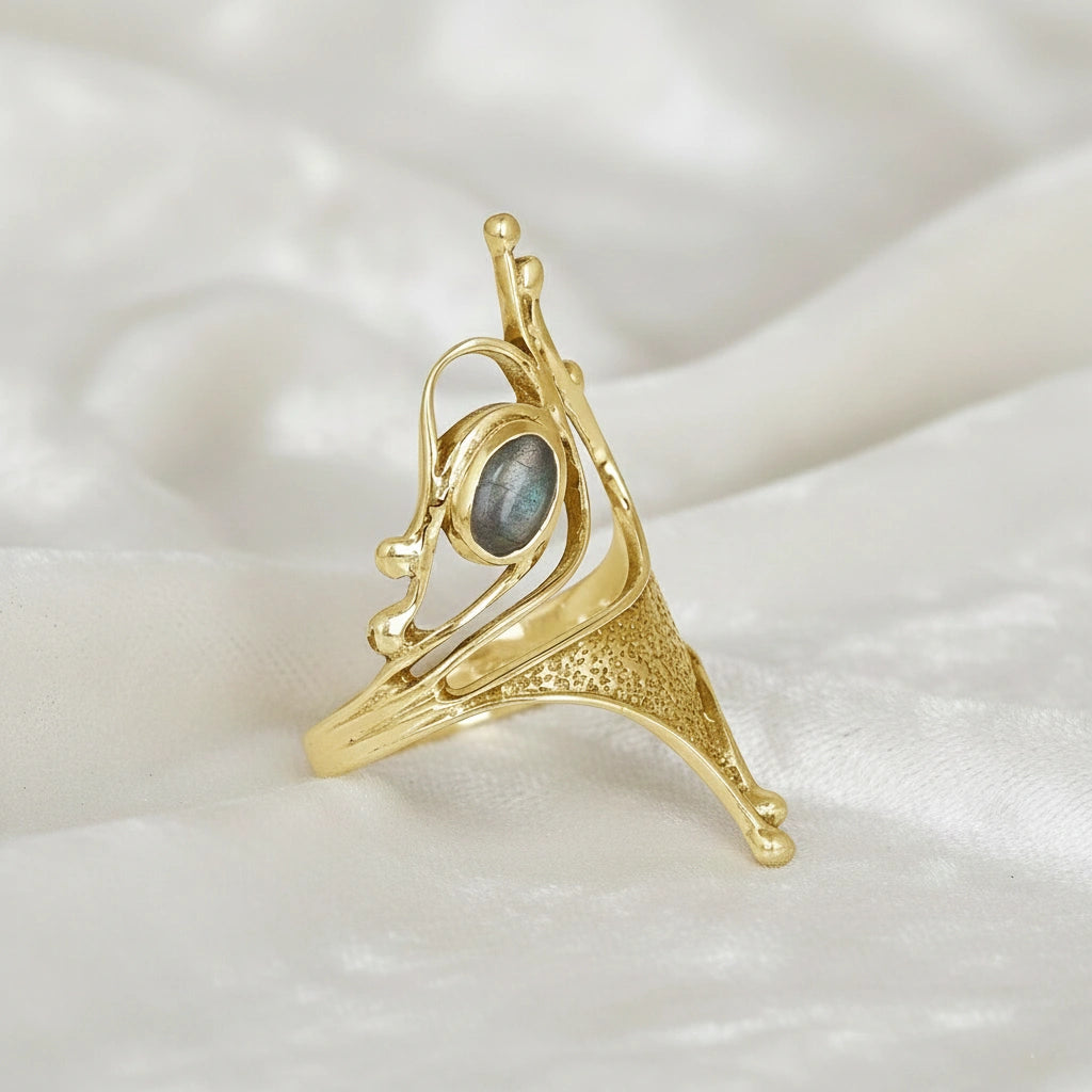 Gold plated sterling silver labradorite ring sculptural design with oval gemstone viewed slightly angled on white fabric