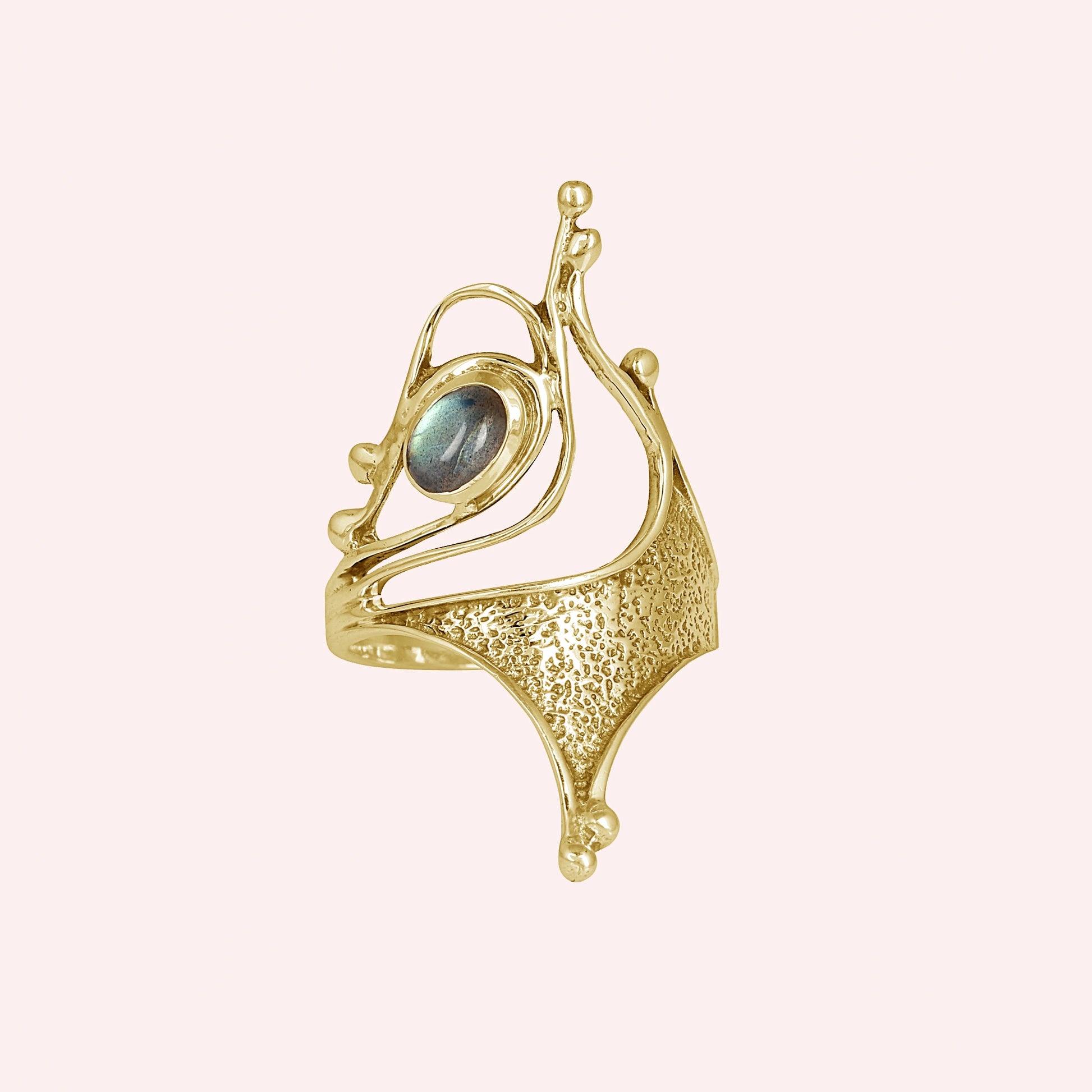 Gold-plated sterling silver labradorite ring with sculptural design and textured metal viewed slightly angled on pink background
