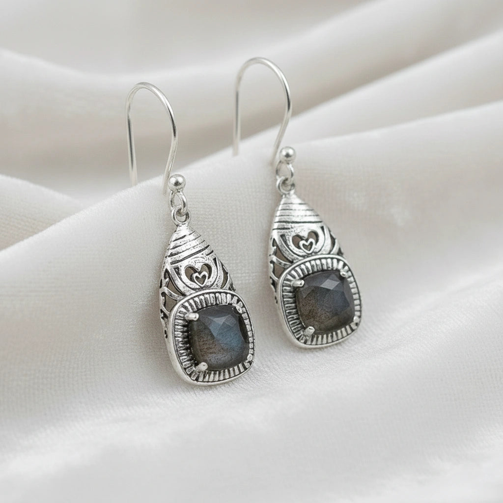Gemstone earrings silver charm studs with a labradorite stones each viewed slightly angled on soft white fabric