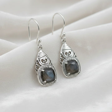 Gemstone earrings silver charm studs with a labradorite stones each viewed slightly angled on soft white fabric