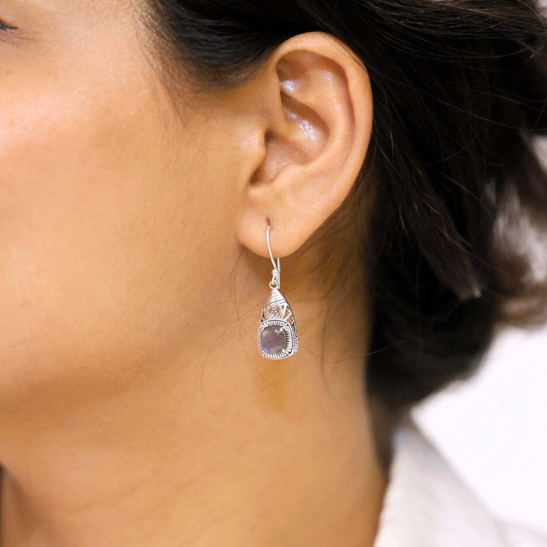 Gemstone earrings silver charm studs with a labradorite stones each viewed slightly angled on soft white fabric