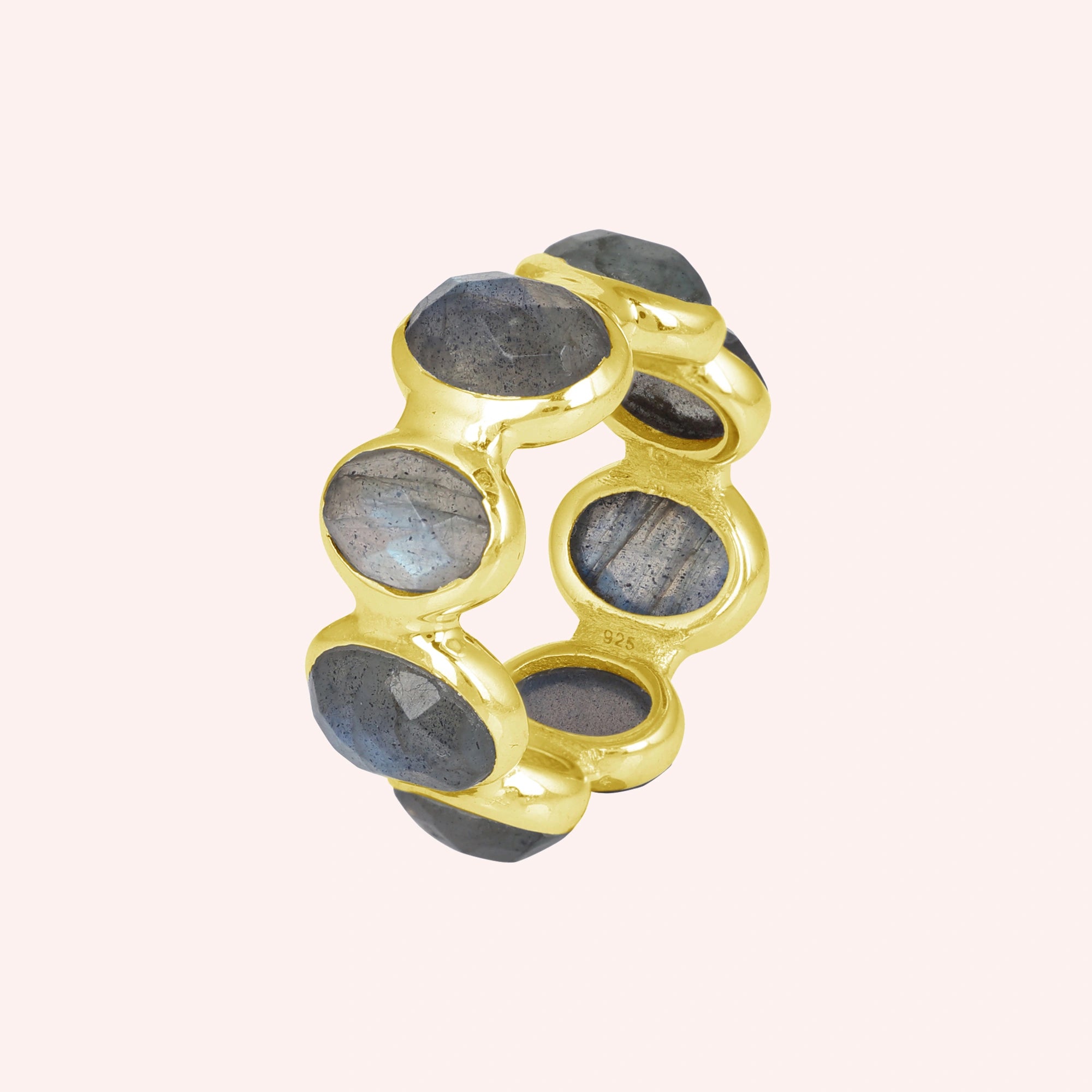 Silver labradorite ring with a thick gold vermeil band and seven large oval iridescent gray blue gemstones on a soft pale pink background.