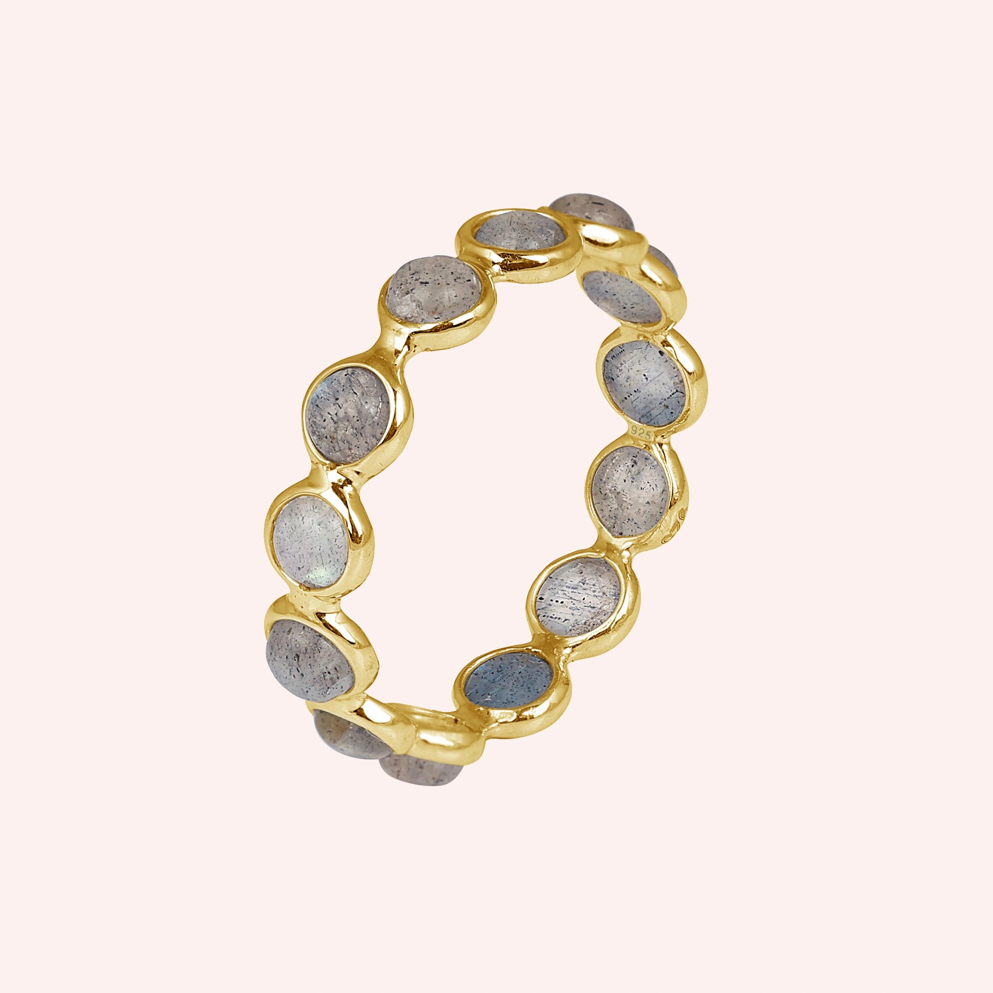Angled shot of a gold-plated sterling silver labradorite ring on a light pink background with round iridescent stones