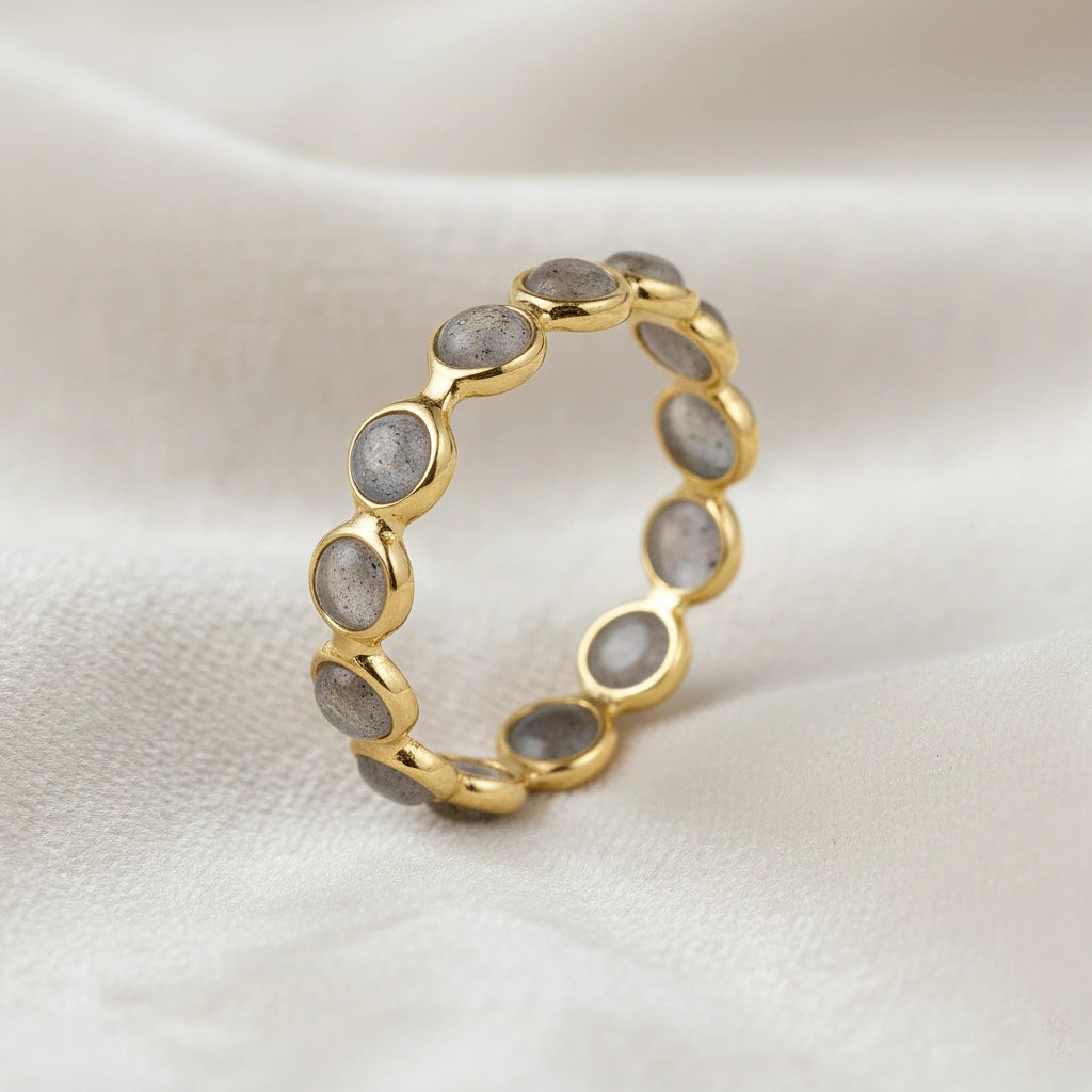 Angled close up shot of a gold-plated sterling silver labradorite ring on a white velvet background with round iridescent stones