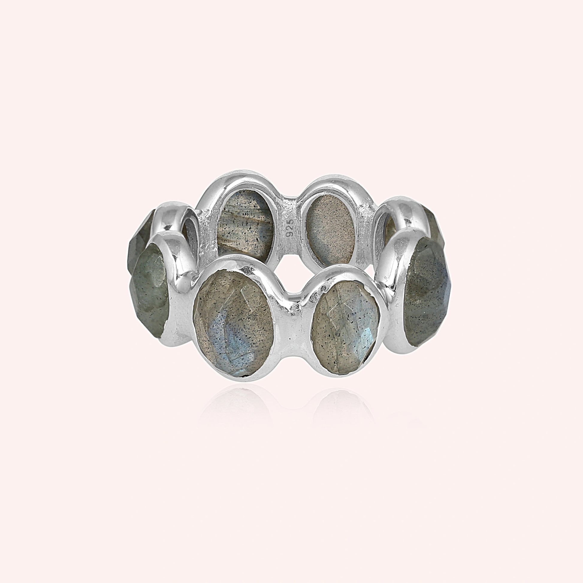 Silver labradorite ring with a bold sterling silver setting and seven large iridescent oval cabochon gemstones on a pale pink background.