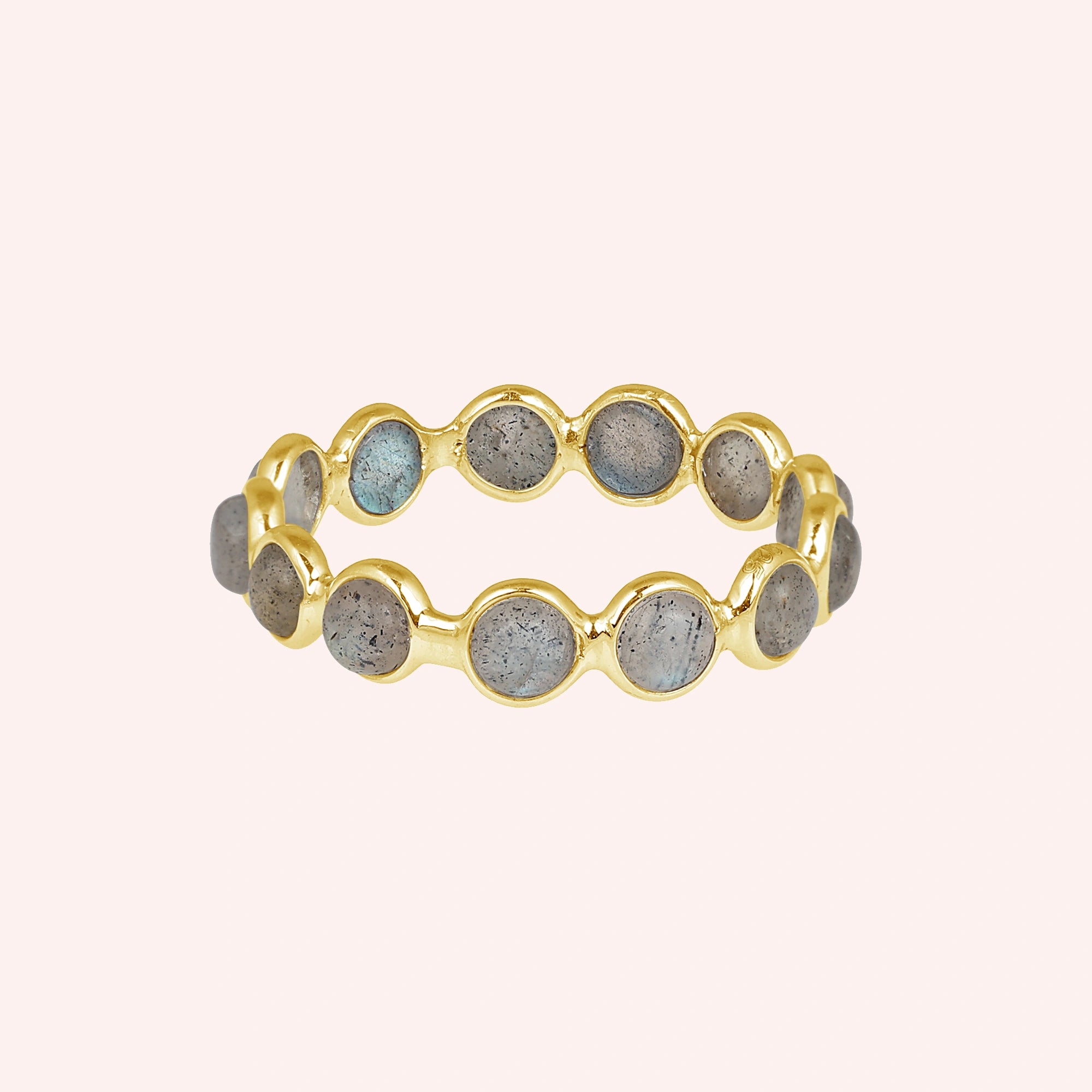 Horizontal shot of a gold-plated sterling silver labradorite ring on a light pink background with round iridescent stones