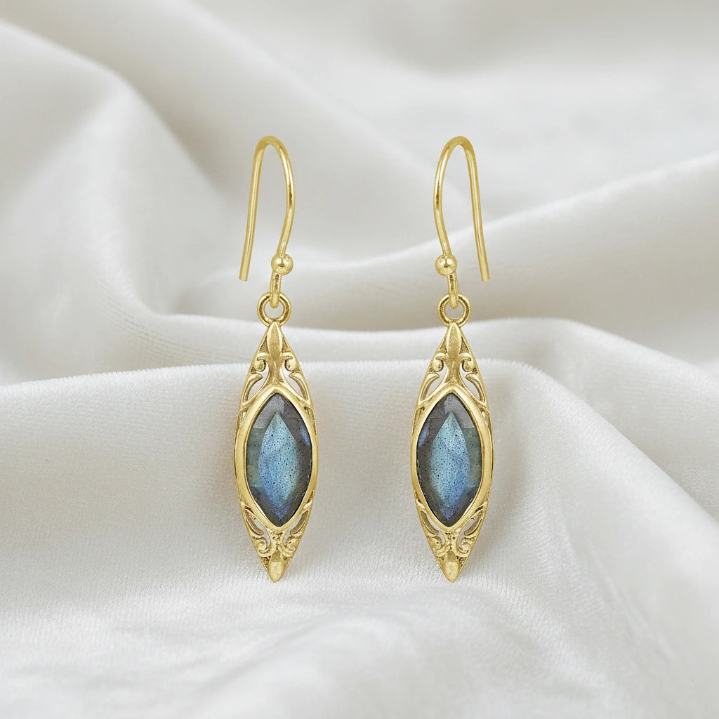 Gold plated marquise earrings dangle design with decorative border and central labradorite viewed straight on soft white fabric