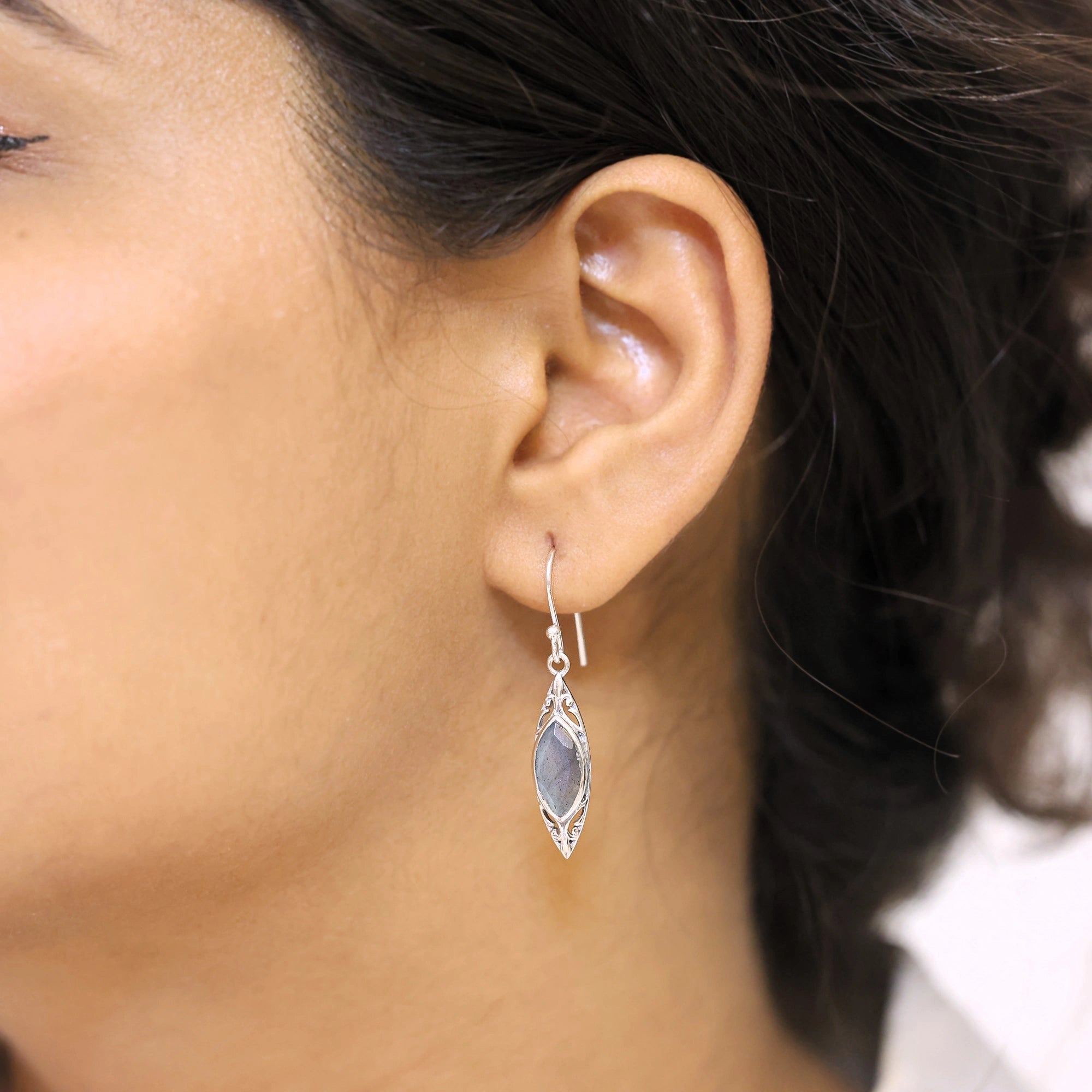 Marquise earrings silver dangle earrings with decorative border and labradorite worn by a model in a side profile