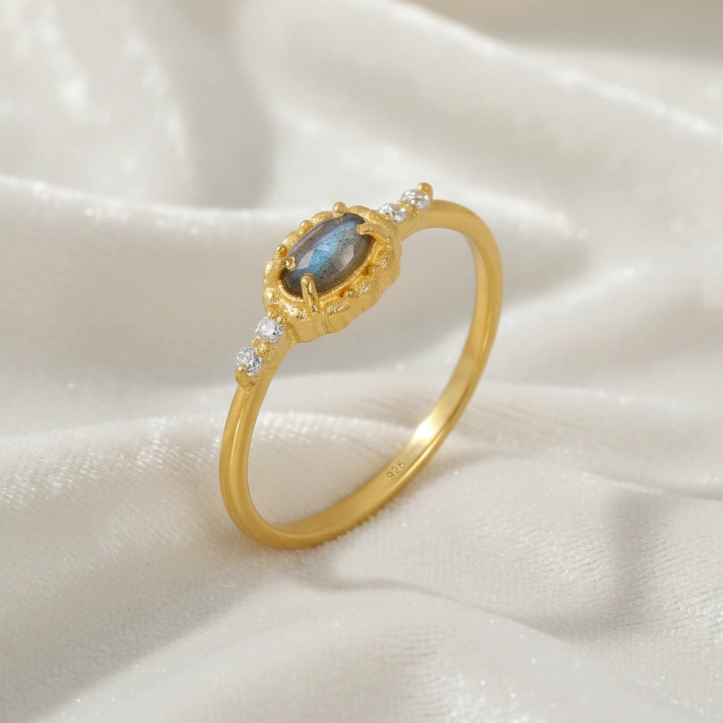 Labradorite-ring-with-white-topaz-stones-gold-plated-silver-angled-view-on-white-satin-background