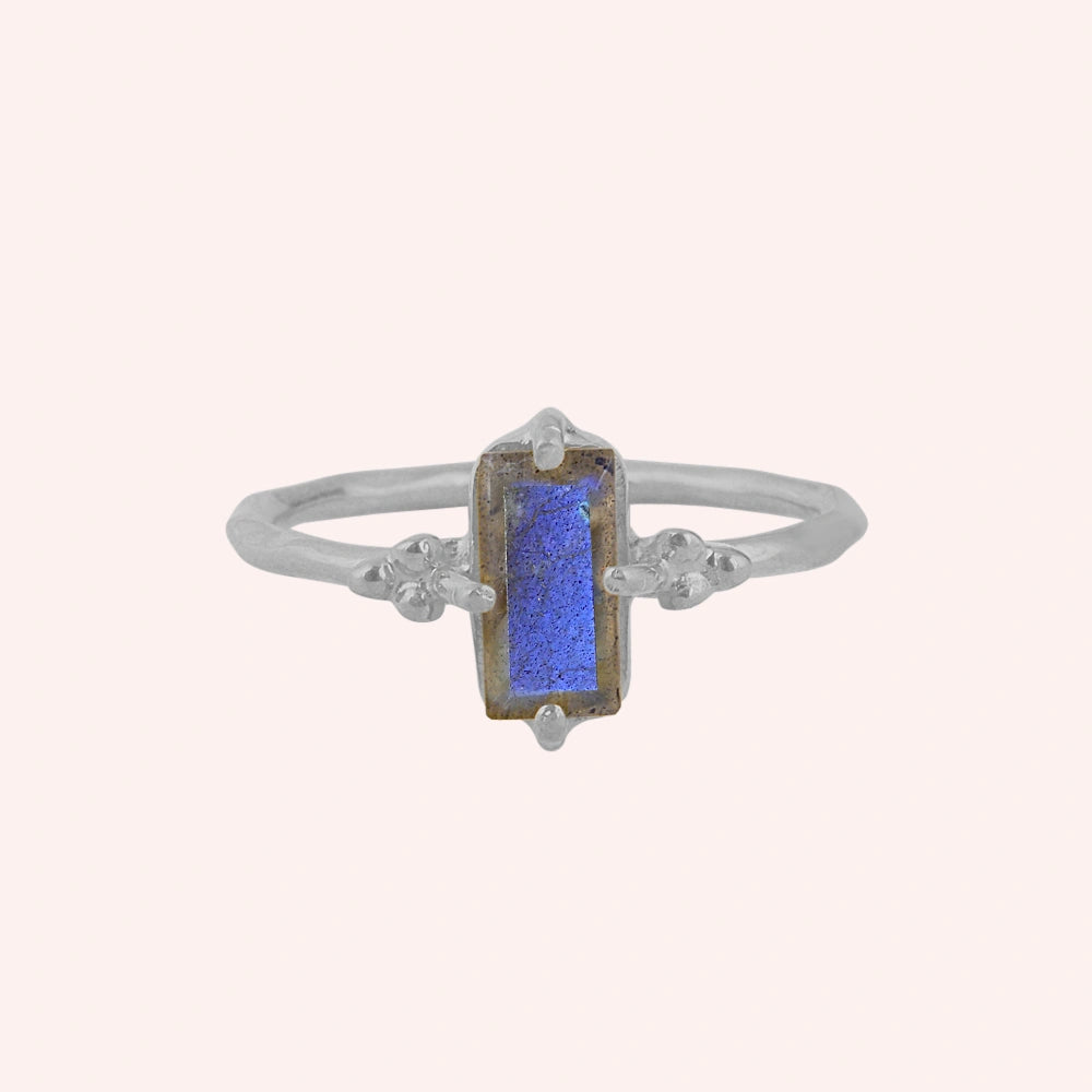 Labradorite_ring_with_baguette_shaped_labradorite_stone_in_sterling_silver_at_front_angle_view_on_solid_pink_background