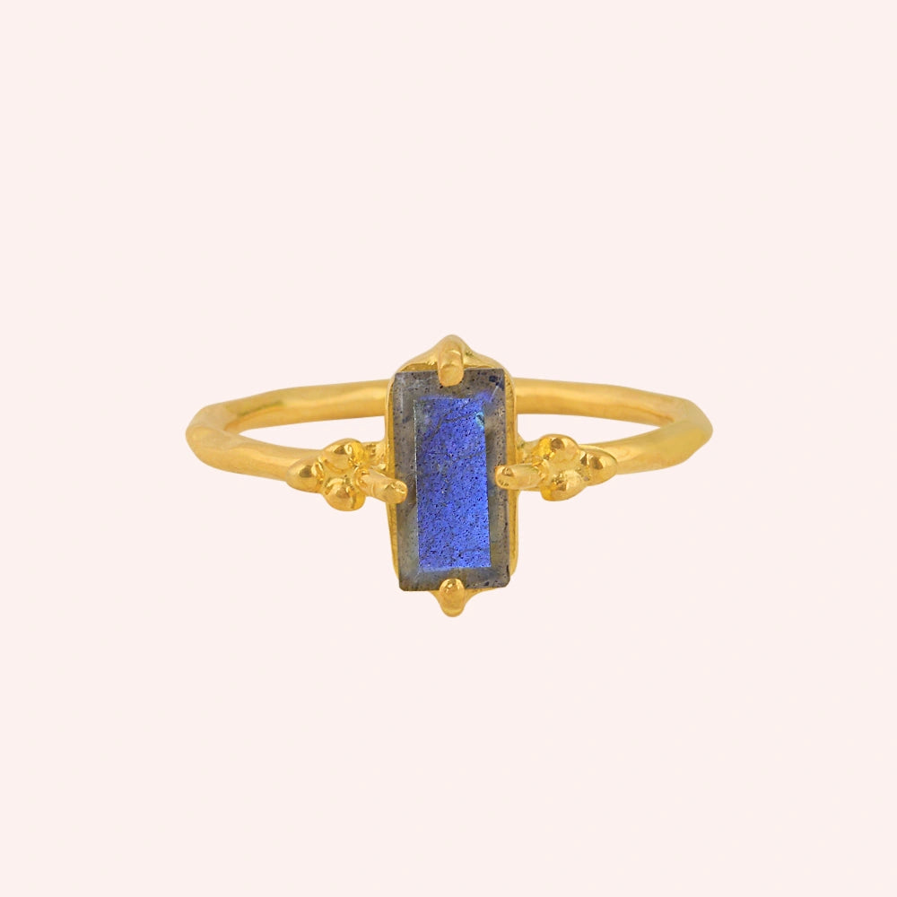 Labradorite_ring_with_baguette_shaped_labradorite_stone_in_gold_plated_silver_at_front_angle_view_on_solid_pink_background