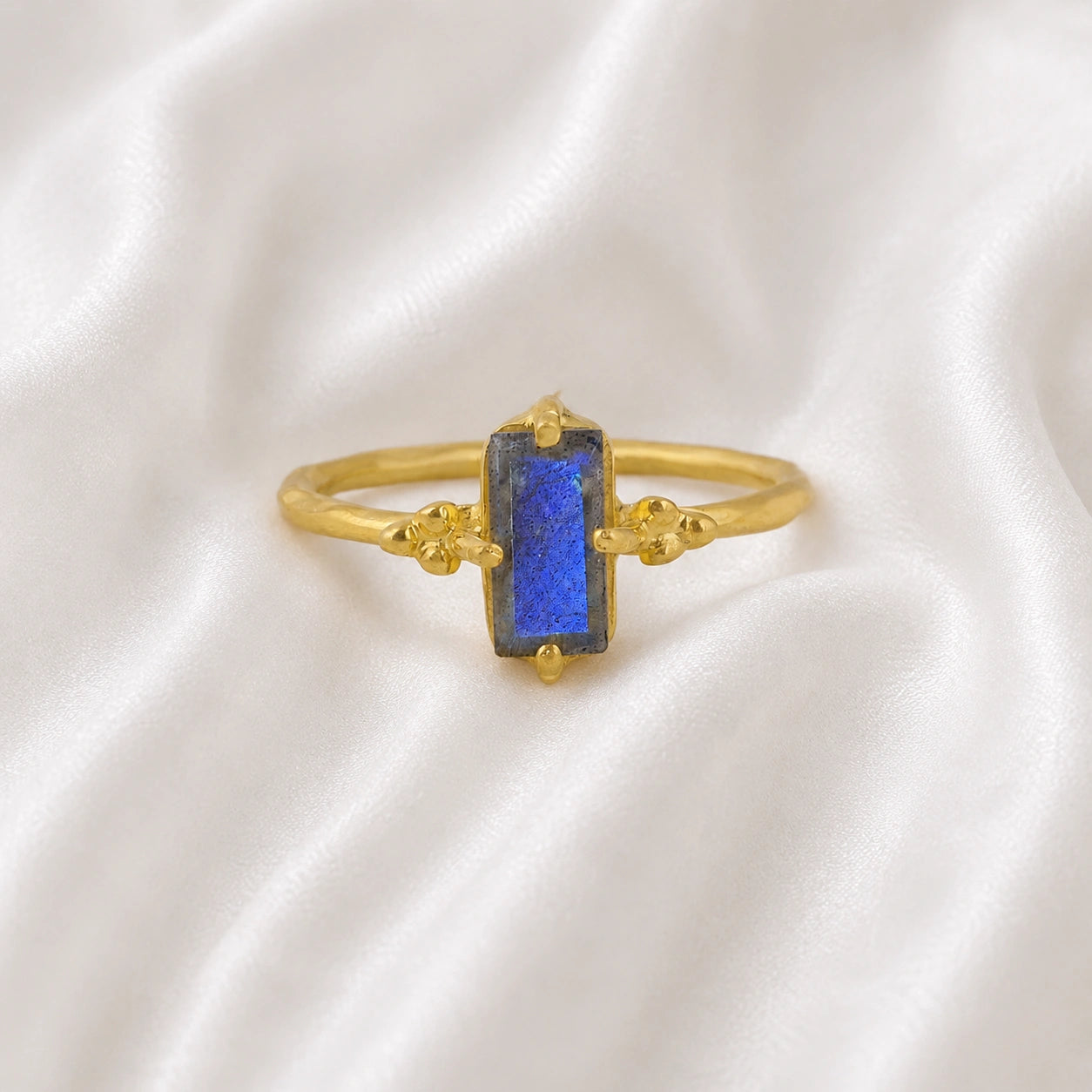 Labradorite_ring_with_baguette_shaped_labradorite_stone_in_gold_plated_silver_at_front_angle_view_on_soft_fabric_background