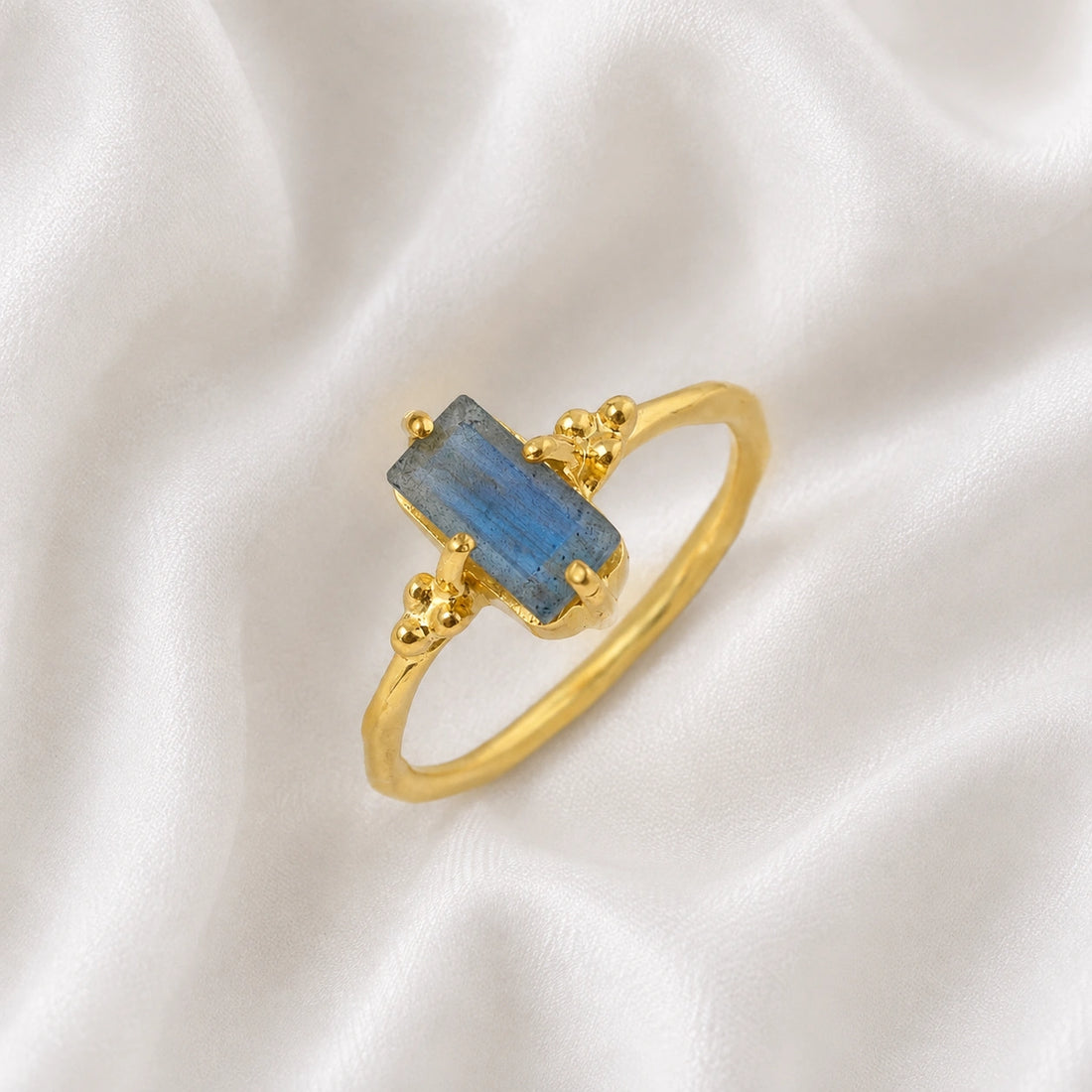 Labradorite_ring_with_baguette_shaped_labradorite_stone_in_gold_plated_silver_at_slight_angle_view_on_soft_fabric_background