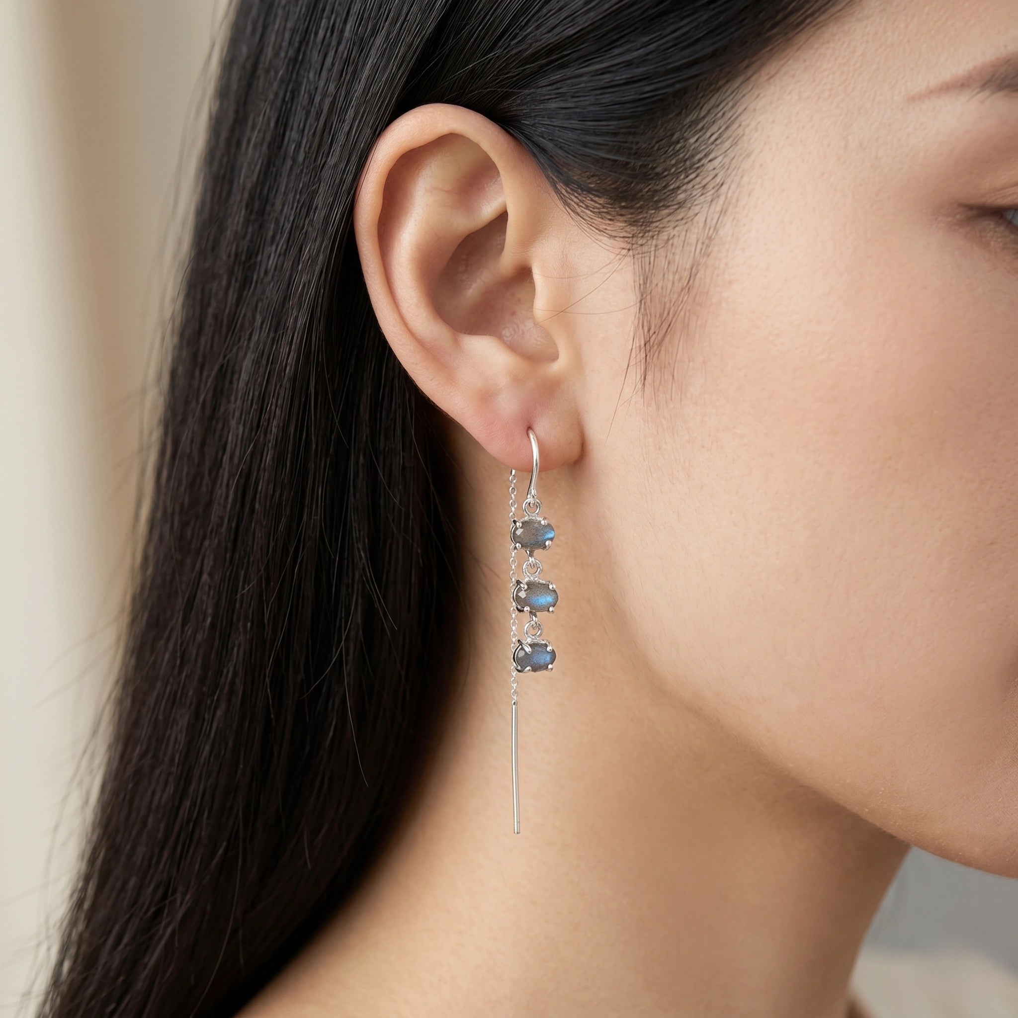 Threader earrings with a silver chain design with three labradorite stones worn by model showing side profile