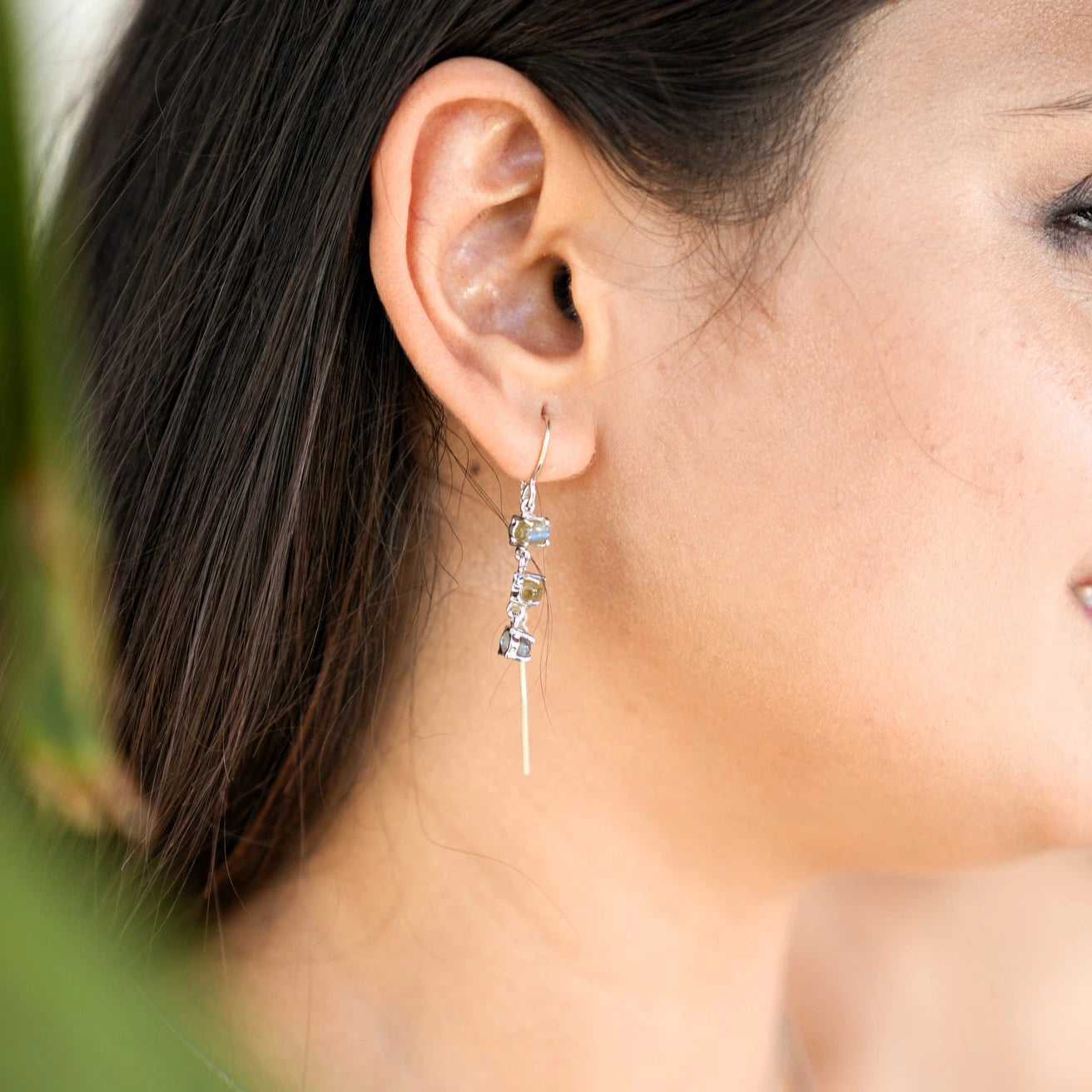 Threader earrings with a silver chain design with three labradorite stones worn by model showing side profile close up