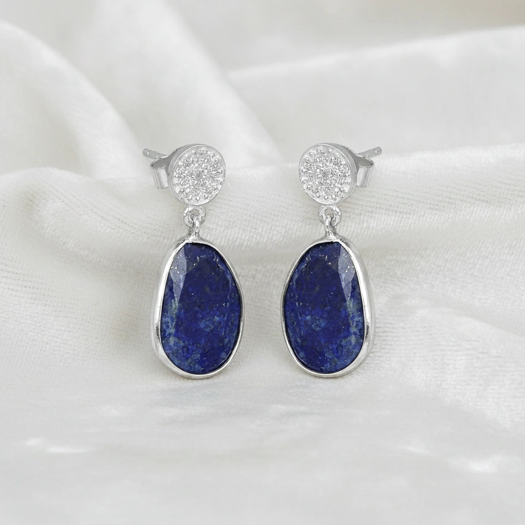 Lapis_lazuli_earrings_in_sterling_silver_with_lapis_lazuli_and_cz_stones_in_slight_angle_on_a_white_fabric_background