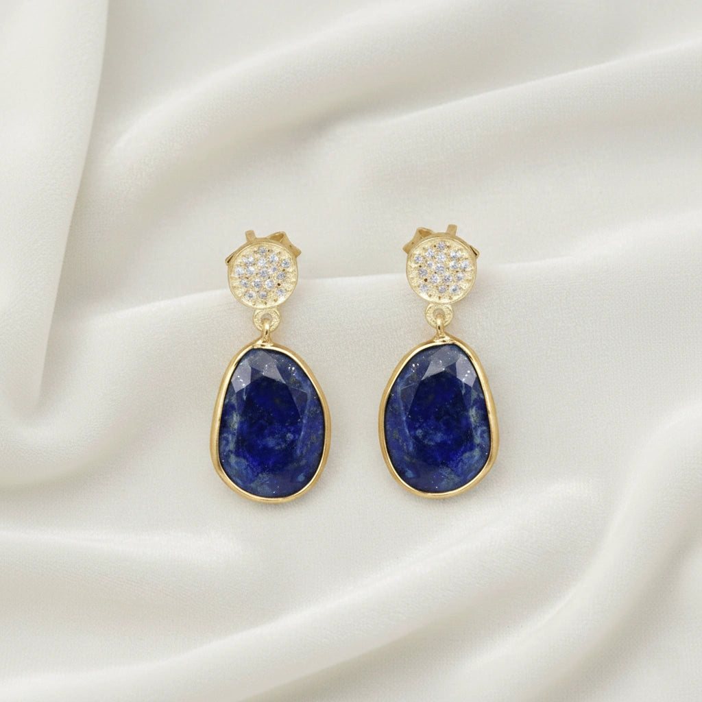 Lapis_lazuli_earrings_in_gold_plated_silver_with_lapis_lazuli_and_cz_stones_in_slight_angle_on_a_white_fabric_background