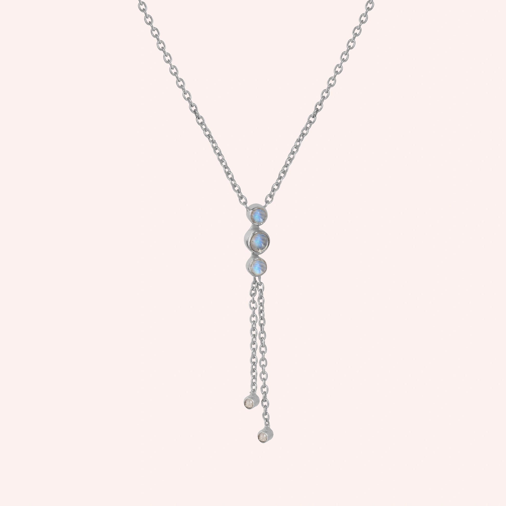 Lariat_necklace_in_sterling_silver_at_slight_angle_featuring_moonstone_drops_on_solid_pink_background