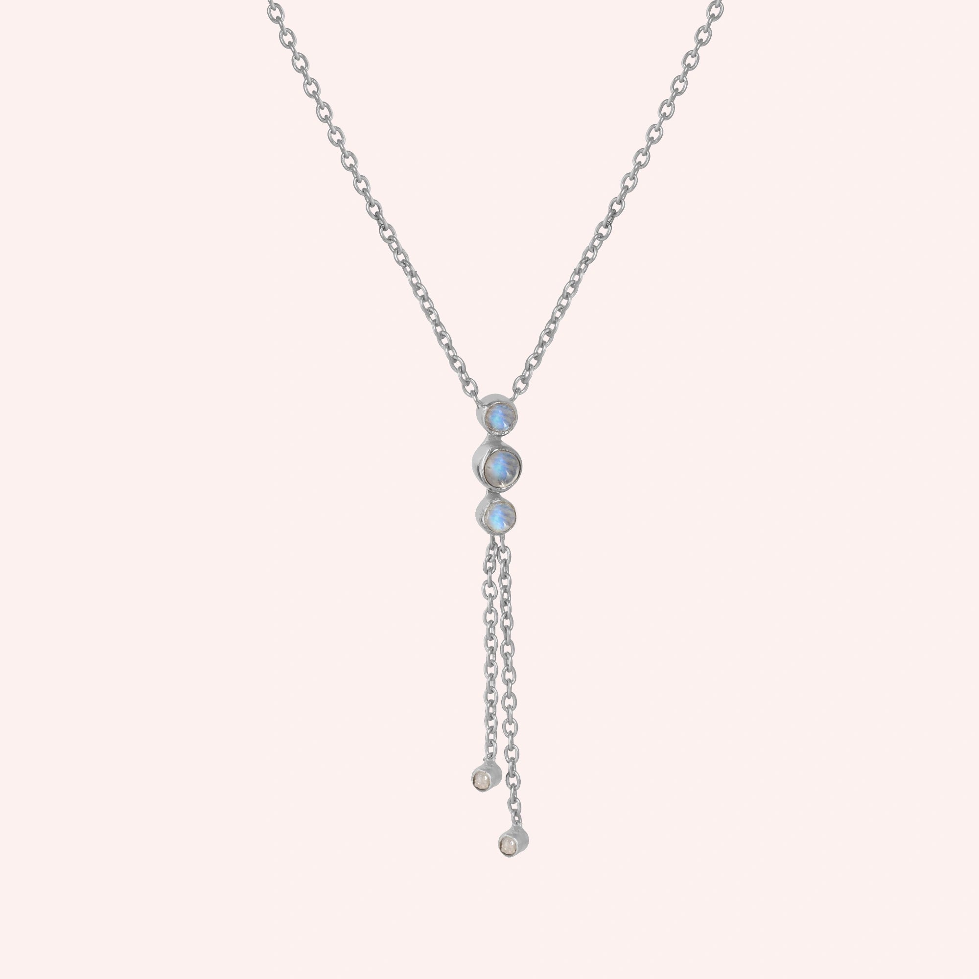 Lariat_necklace_in_sterling_silver_at_slight_angle_featuring_moonstone_drops_on_solid_pink_background