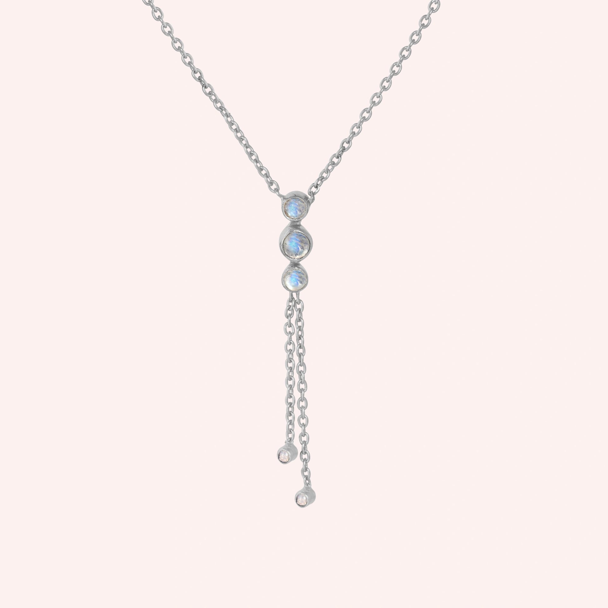 Lariat_necklace_in_sterling_silver_at_front_angle_featuring_moonstone_drops_on_solid_pink_background