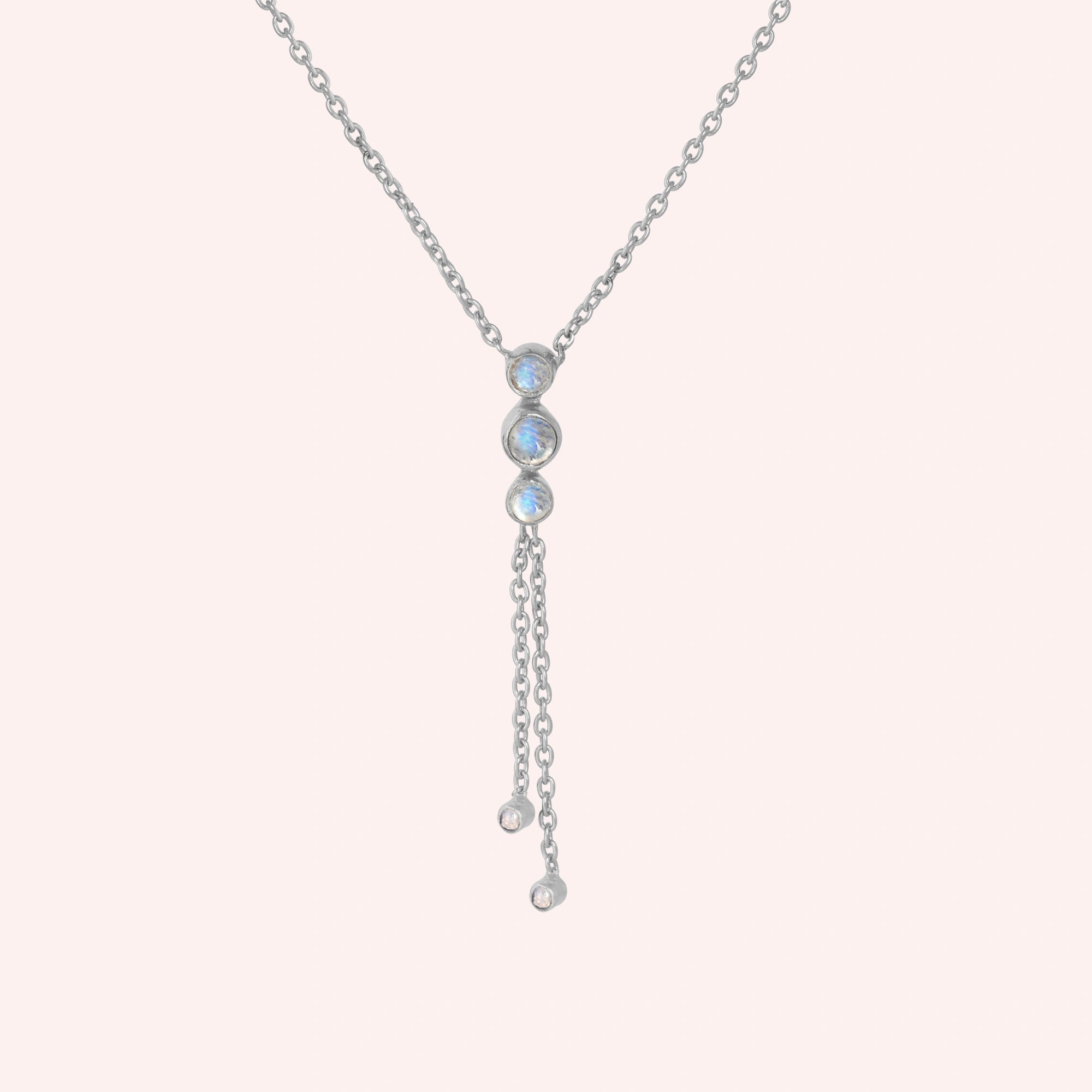 Lariat_necklace_in_sterling_silver_at_front_angle_featuring_moonstone_drops_on_solid_pink_background