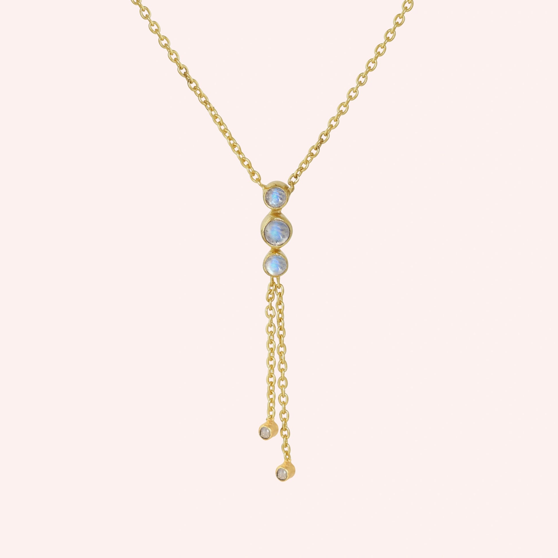 Lariat_necklace_in_gold_plated_silver_at_front_angle_featuring_moonstone_drops_on_solid_pink_background