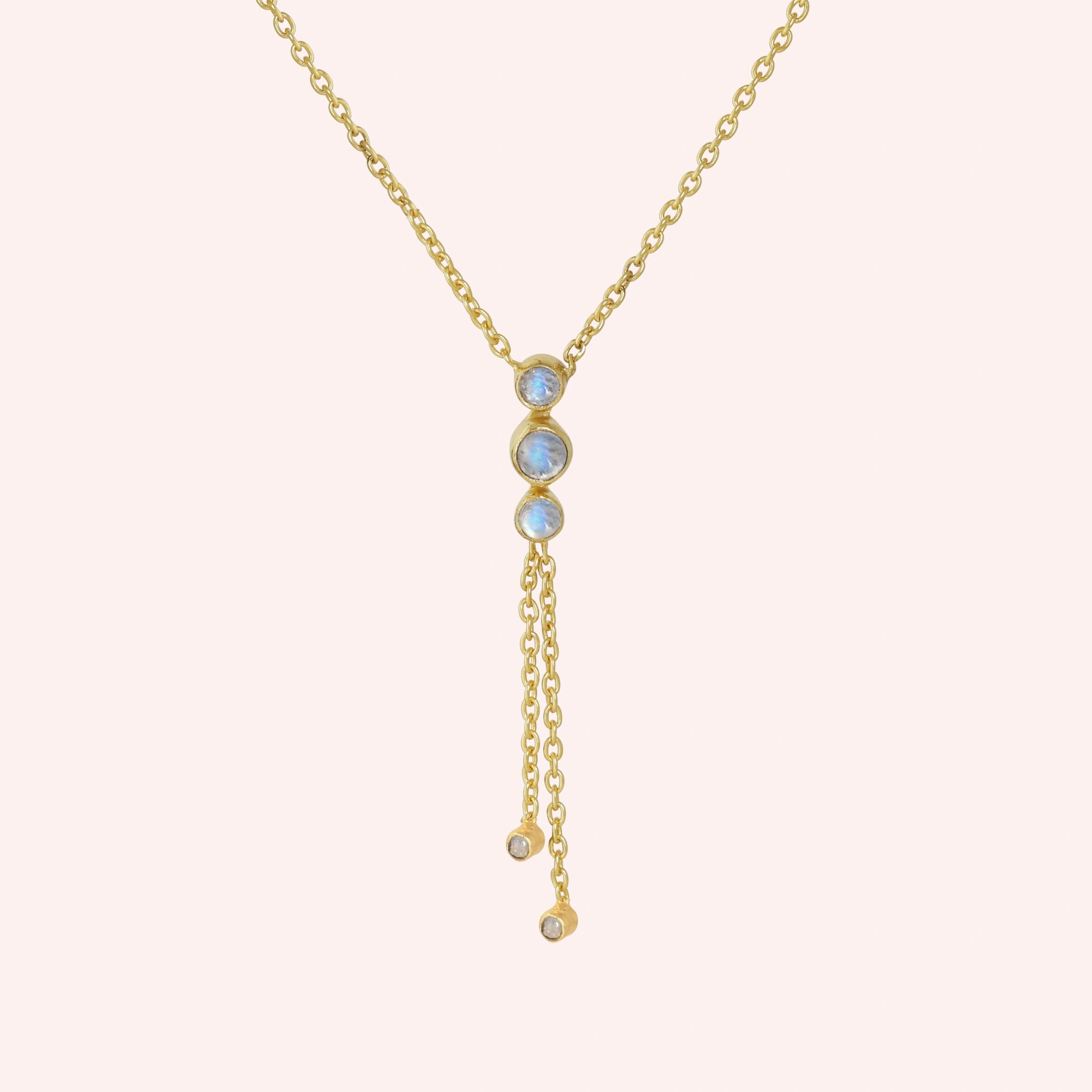 Lariat_necklace_in_gold_plated_silver_at_front_angle_featuring_moonstone_drops_on_solid_pink_background