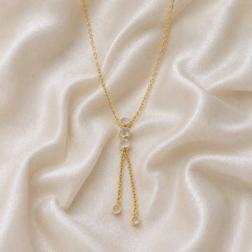 Lariat_necklace_in_gold_plated_silver_at_front_angle_featuring_moonstone_drops_on_soft_fabric_background
