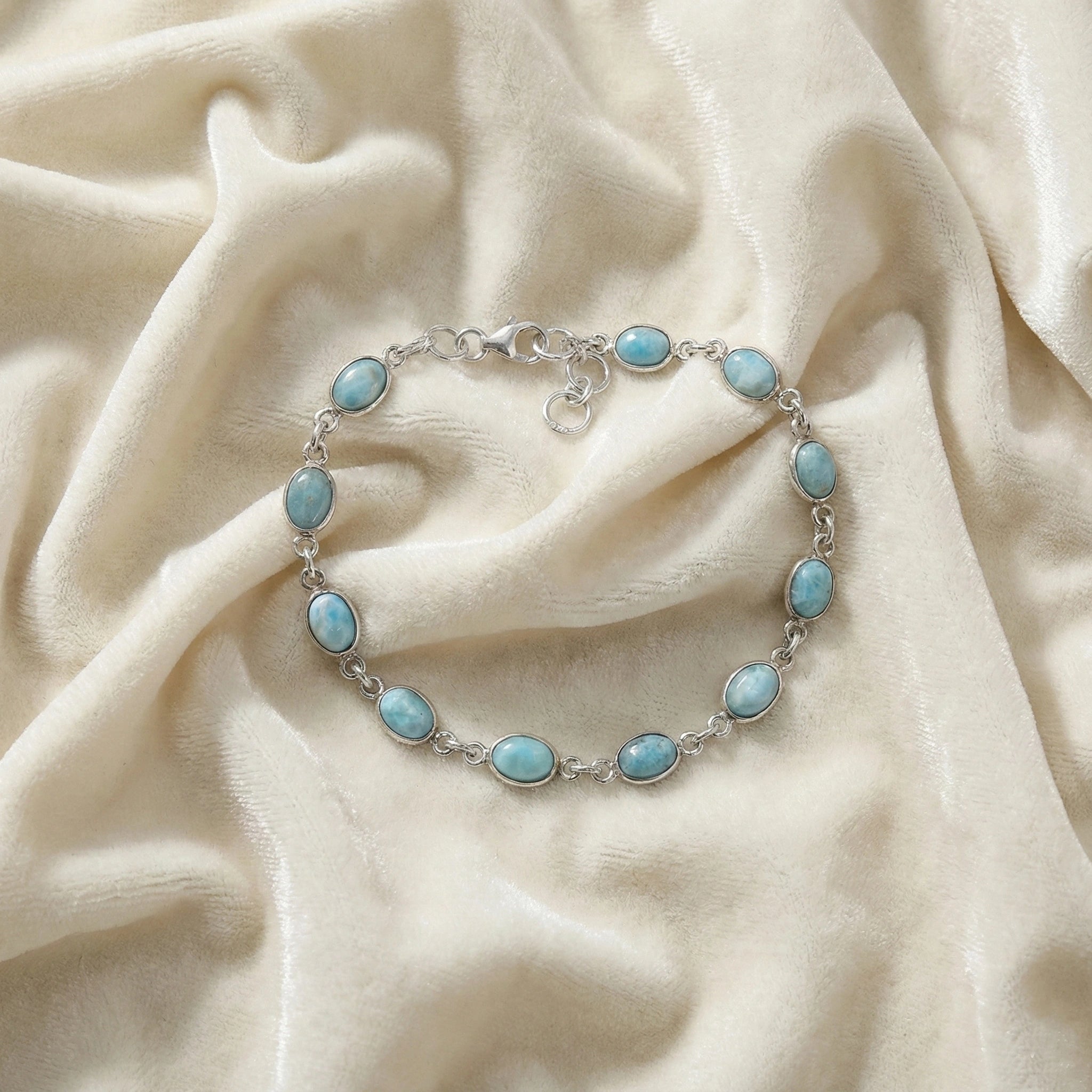 Larimar bracelet sterling silver oval links gemstone chain on an off white velvet fabric from a straight angle view