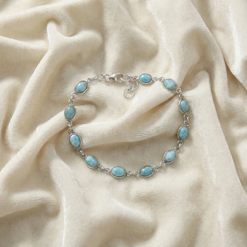 Larimar bracelet sterling silver oval links gemstone chain on an off white velvet fabric from a straight angle view