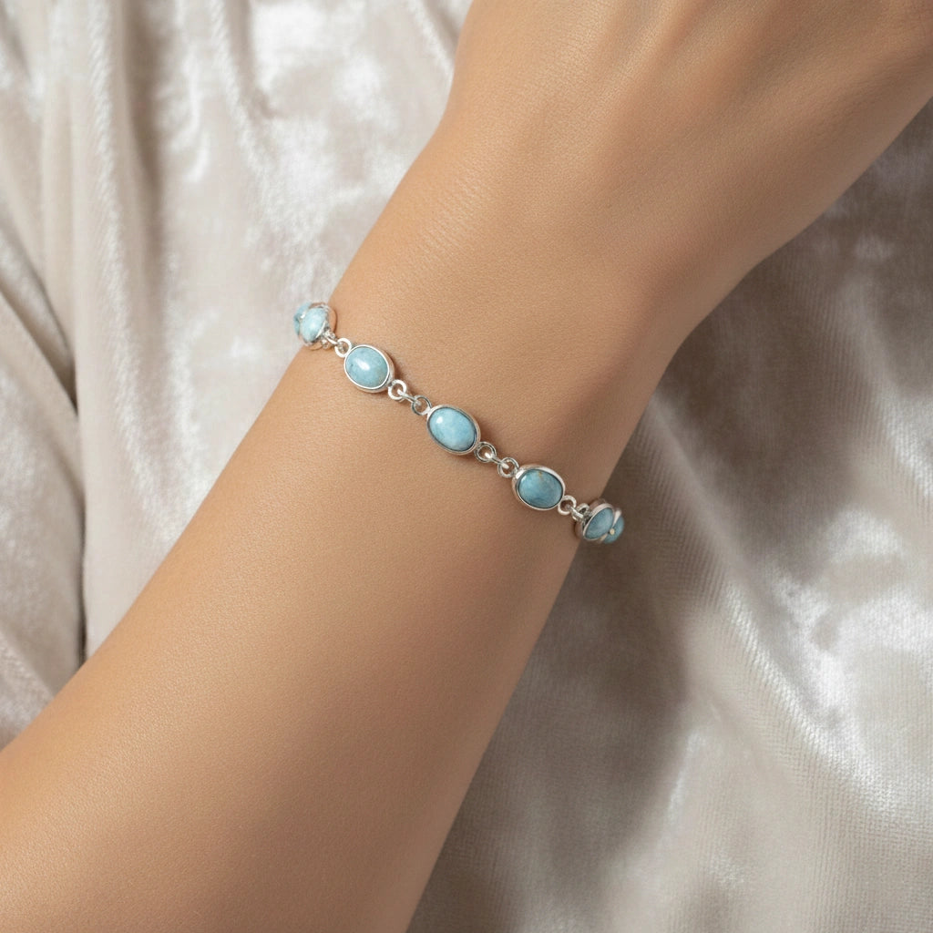 Larimar bracelet sterling silver oval links gemstone chain on an off white velvet fabric from a straight angle view