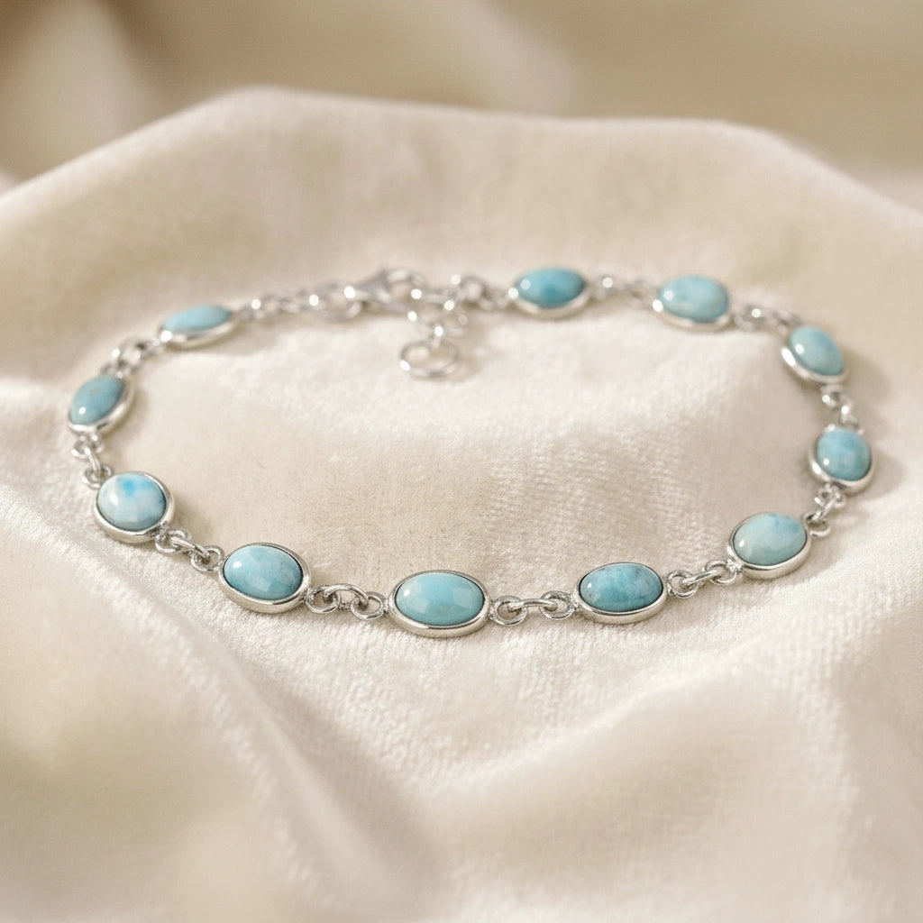 Larimar bracelet sterling silver oval links gemstone chain on an off white draped fabric from a straight angle view