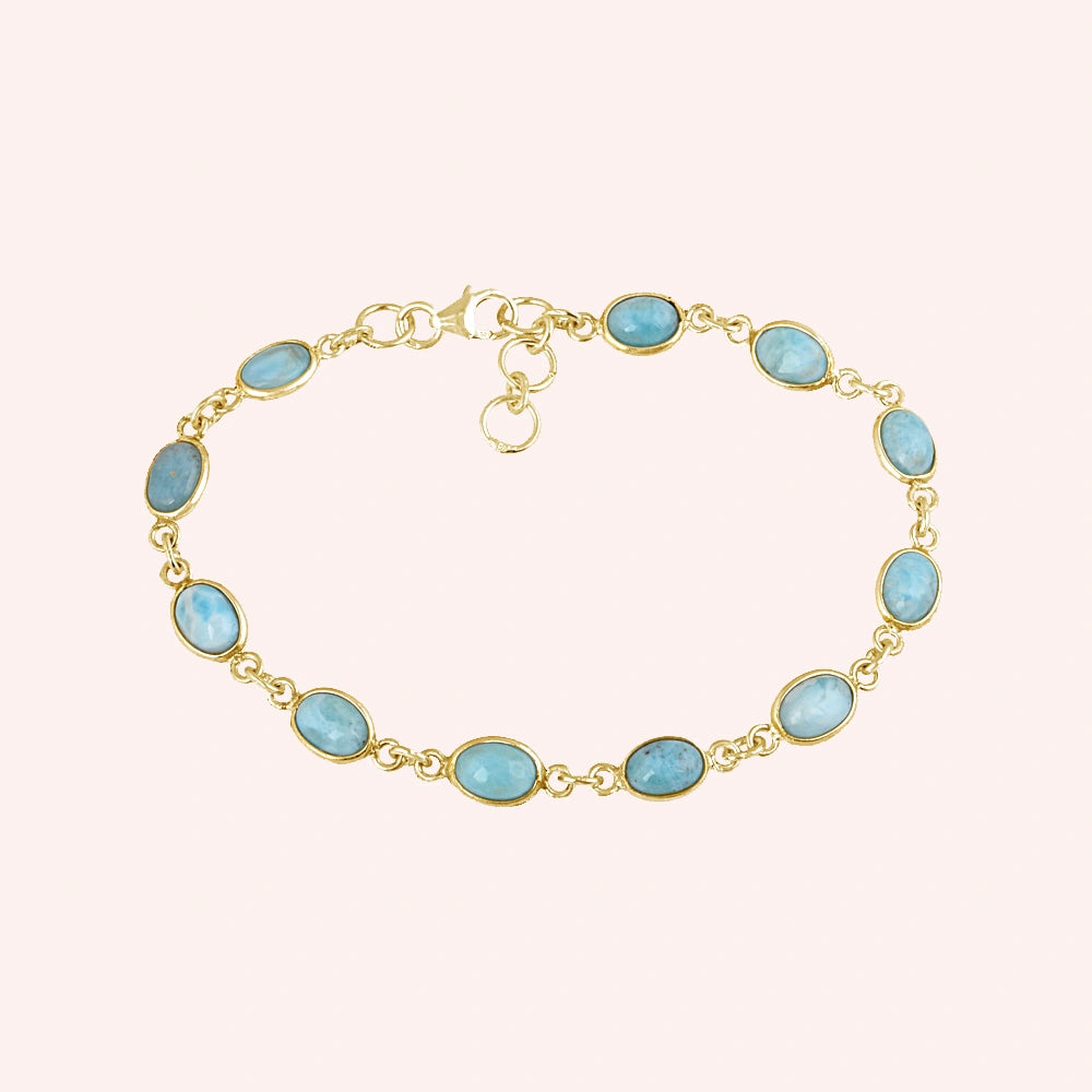 Gold plated Larimar bracelet with oval links gemstone chain on light pink background from a straight product angle view