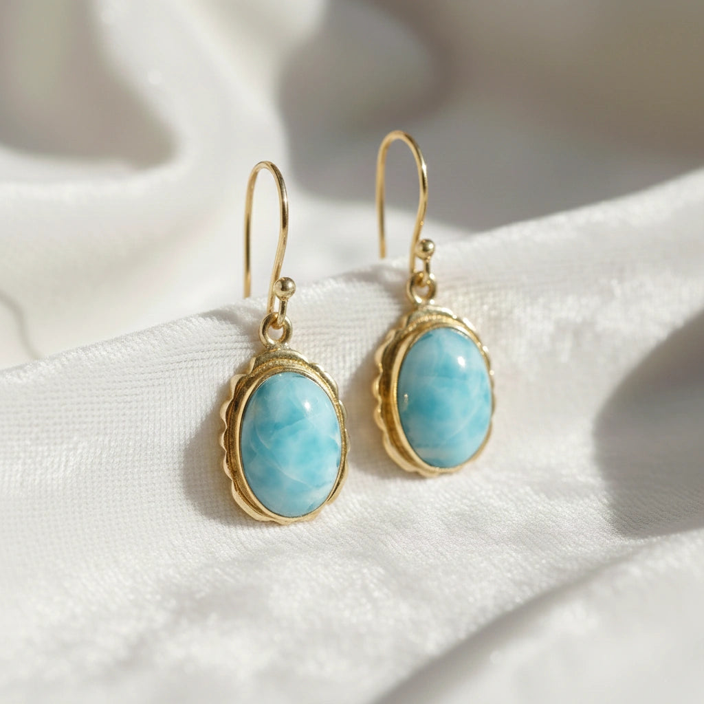 Silver dangling earring with cushion cut larimar gemstones with gold plating on white draped fabric from straight view