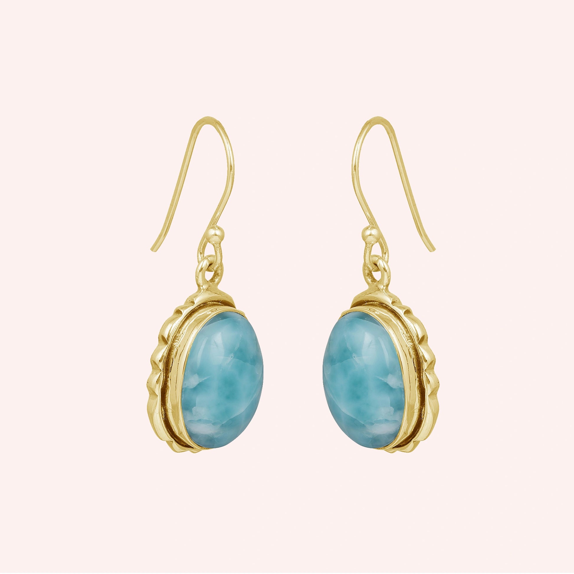 Silver dangling earring with oval larimar gemstones with gold plating on light pink background from a side angle view
